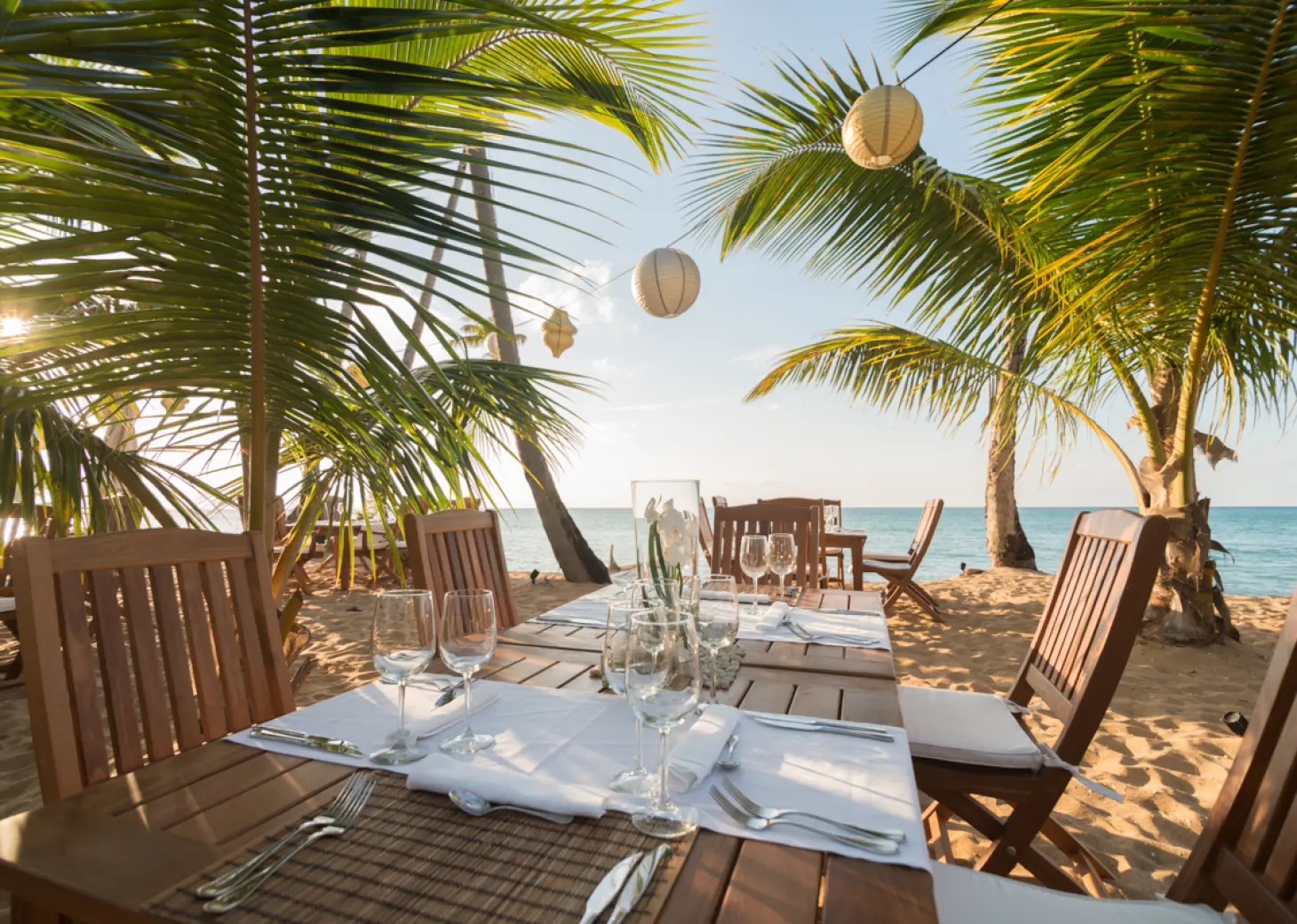 Beachfront wedding reception tables under palm trees at Sublime Samana, Samana