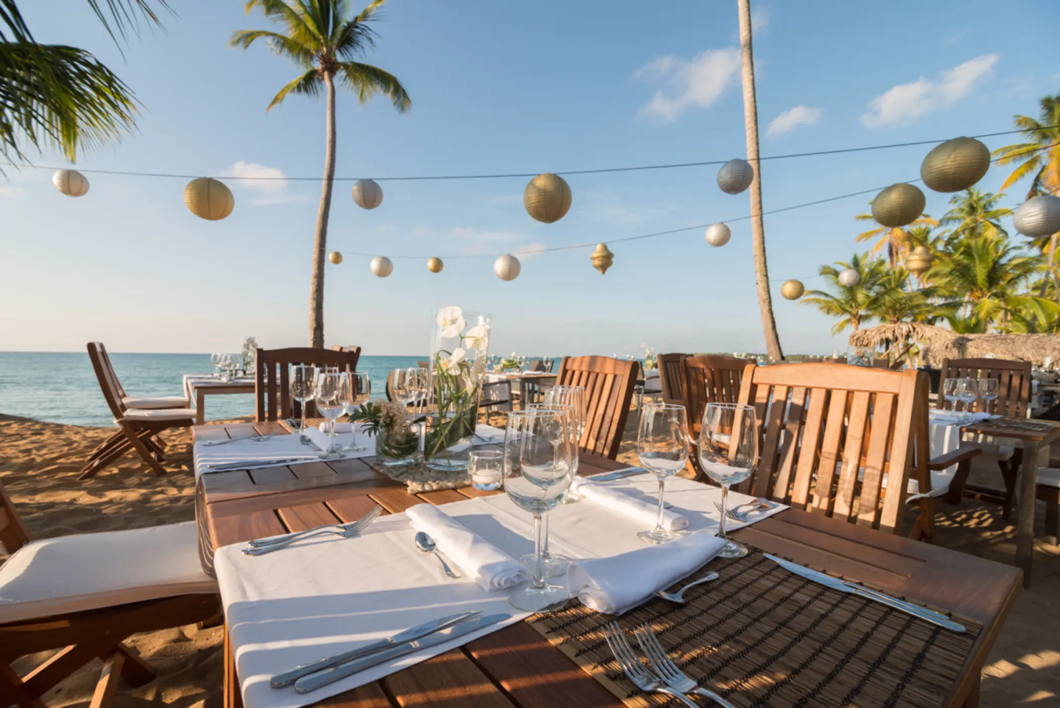 Beachfront wedding reception tables with paper lanterns at Sublime Samaná, Samana