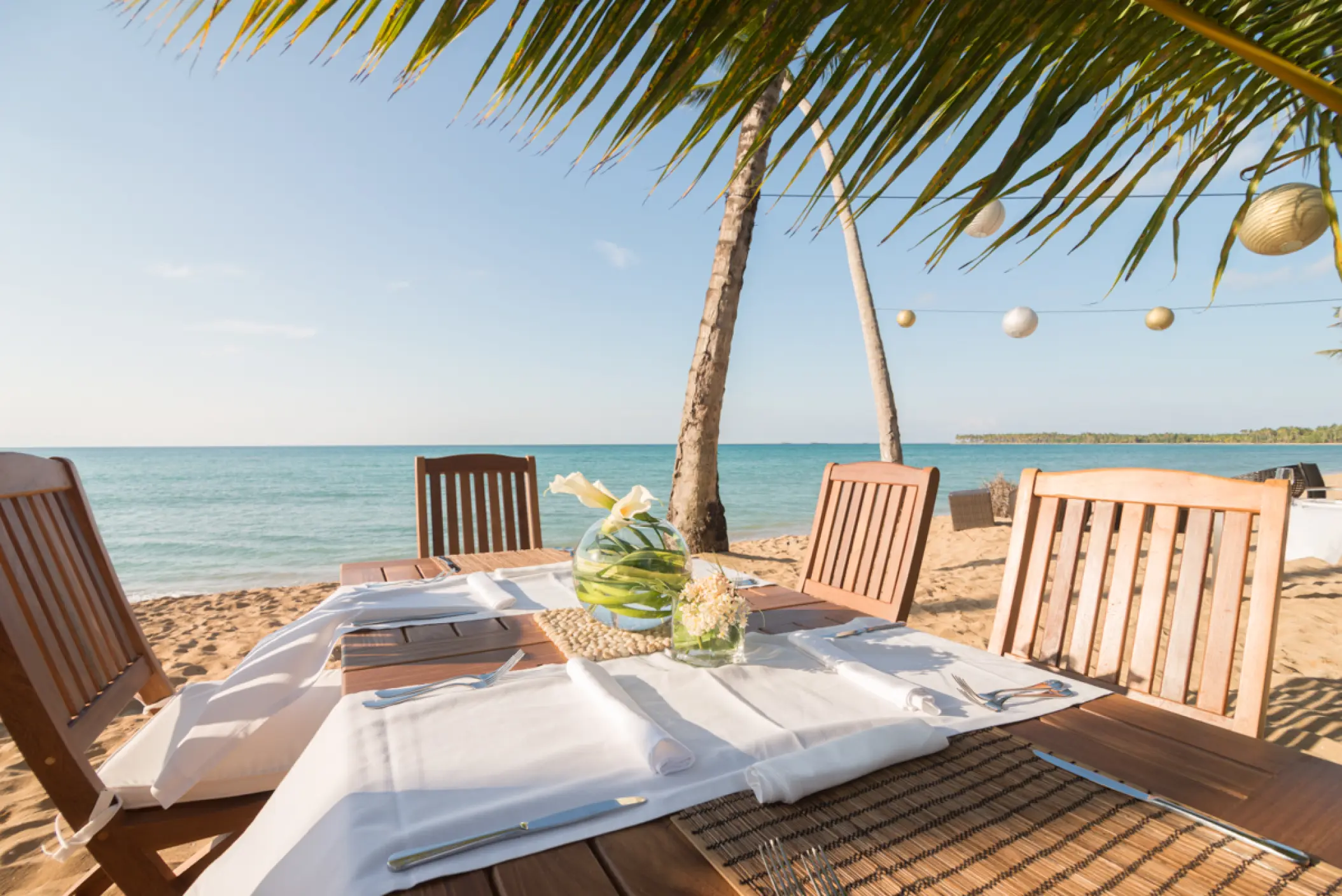 Beachfront wedding reception table under palm trees at Sublime Samana, Samana