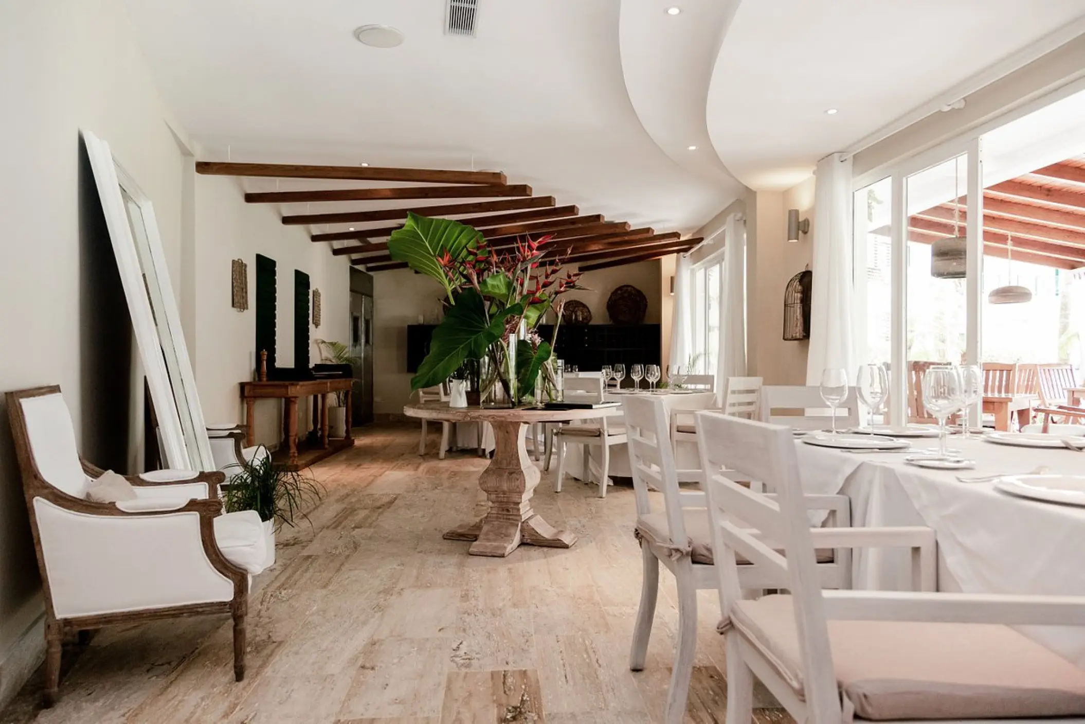 Bistro dining room with white chairs and floral centerpiece at Sublime Samaná, Samana