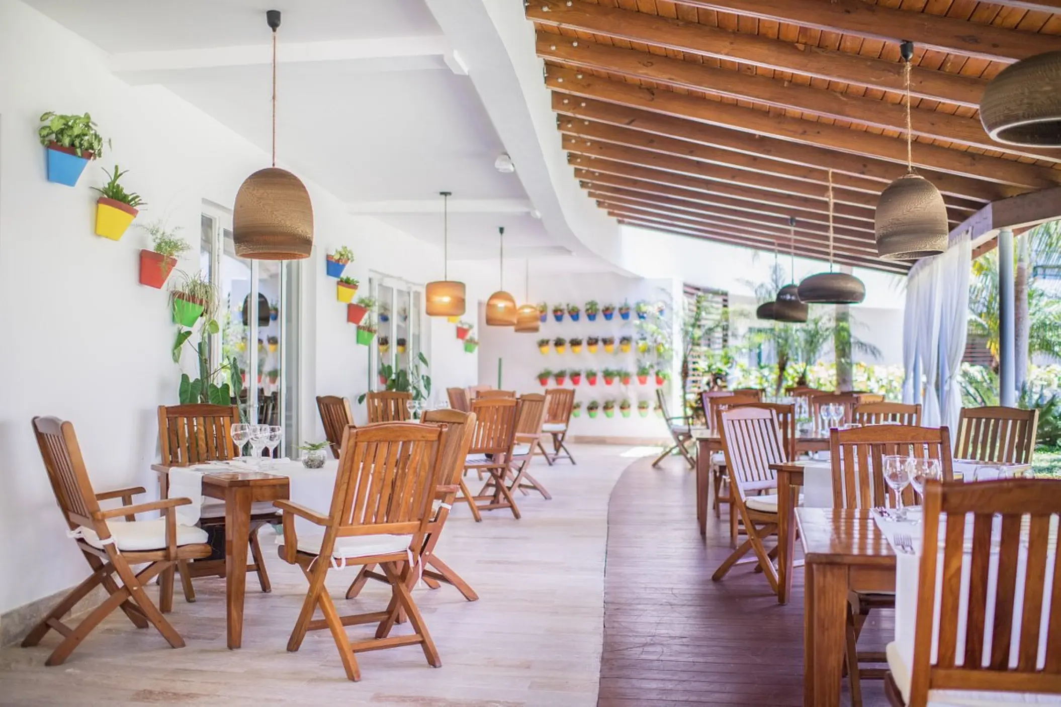 Bistro terrace with wooden tables and potted plants at Sublime Samaná, Samana