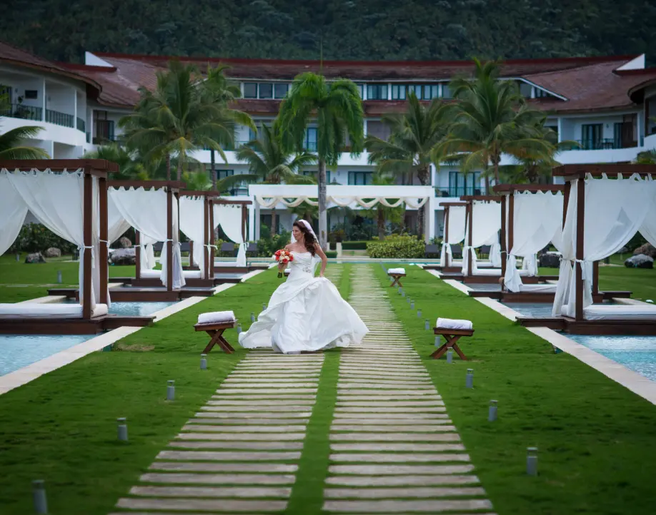 Bride walking down a stone path between pool cabanas at Sublime Samana, Samana