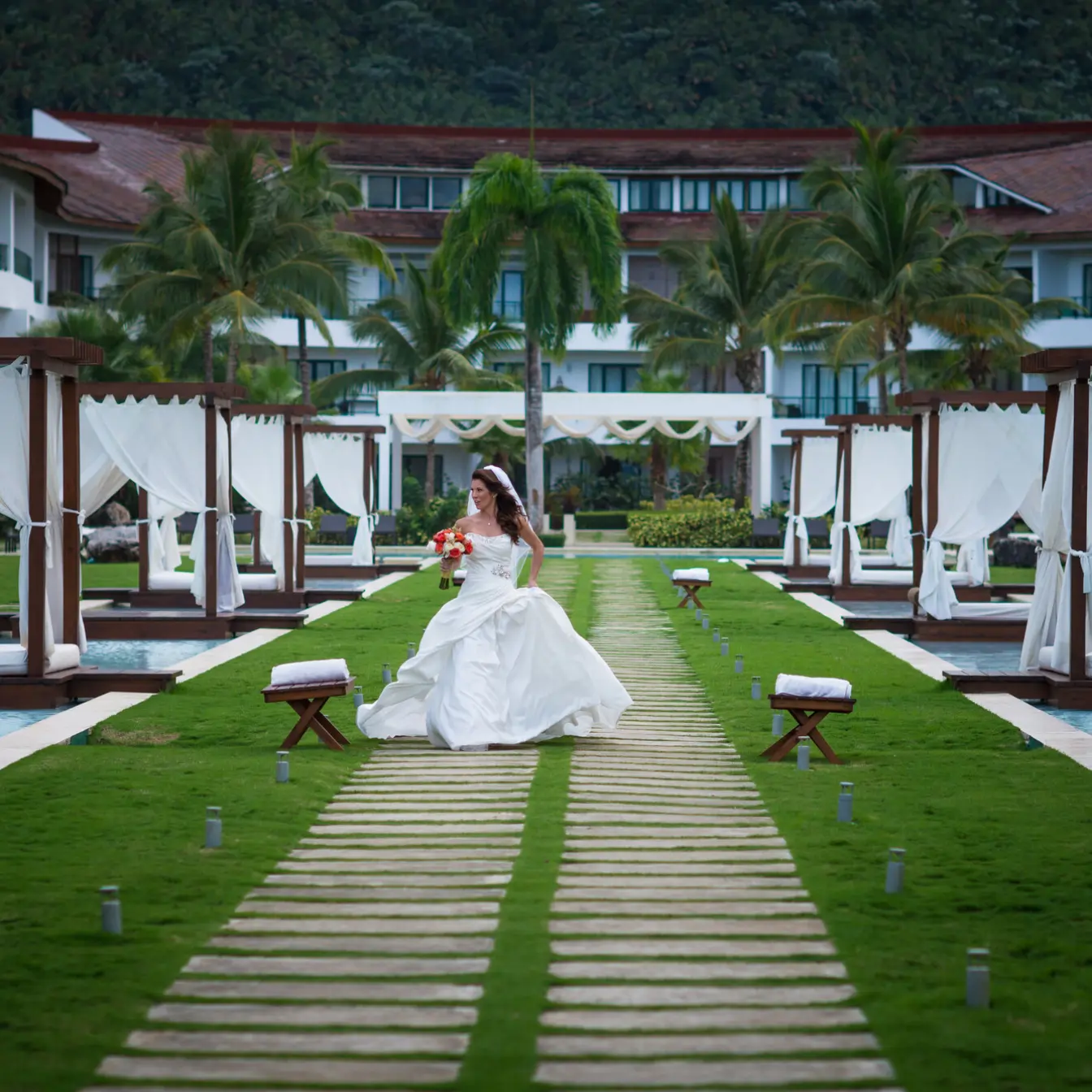 Bride walking down a stone path between pool cabanas at Sublime Samana, Samana