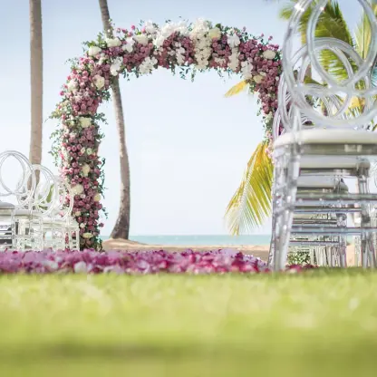 Floral wedding ceremony arch and clear acrylic chairs at Sublime Samaná, Samana
