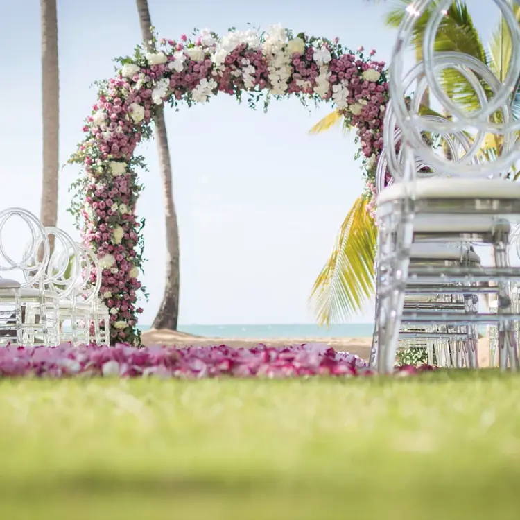 Floral wedding ceremony arch and clear acrylic chairs at Sublime Samaná, Samana