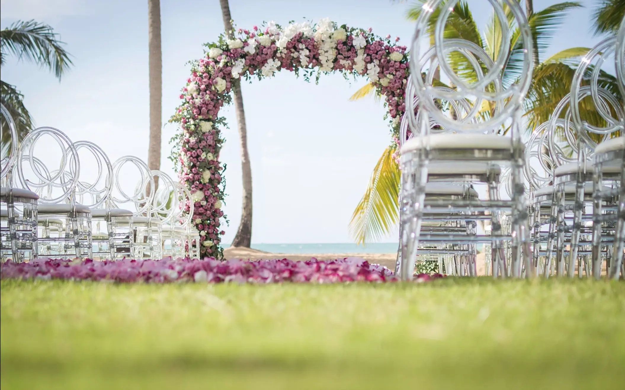 Floral wedding ceremony arch and clear acrylic chairs at Sublime Samaná, Samana