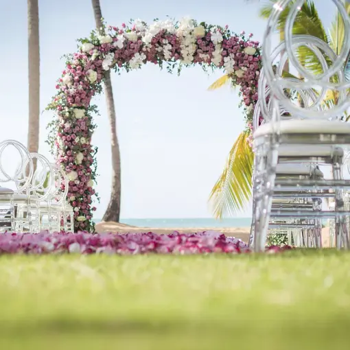 Floral wedding ceremony arch and clear acrylic chairs at Sublime Samaná, Samana