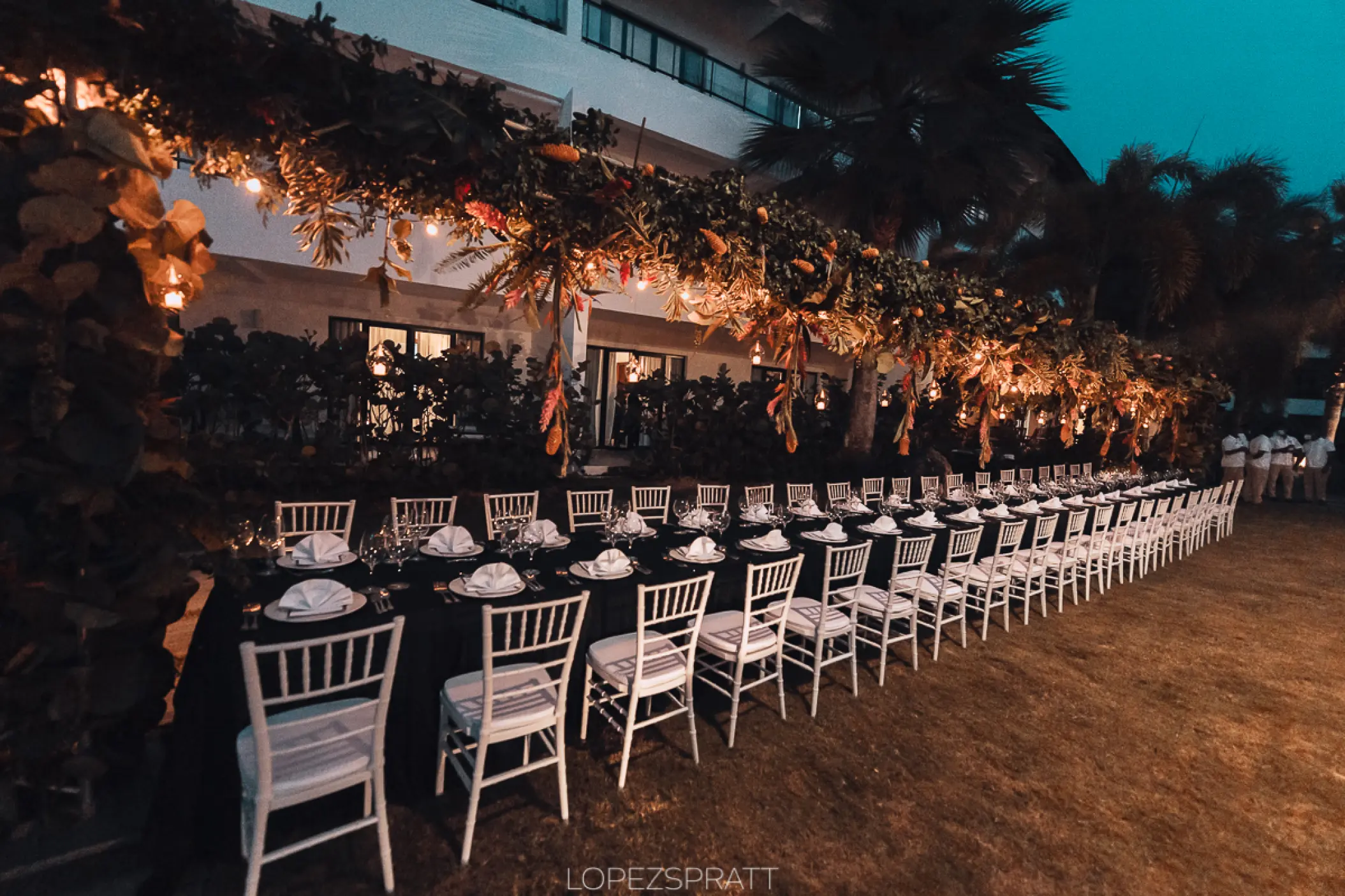 Long garden wedding reception table with floral canopy and string lights at Sublime Samana, Samana
