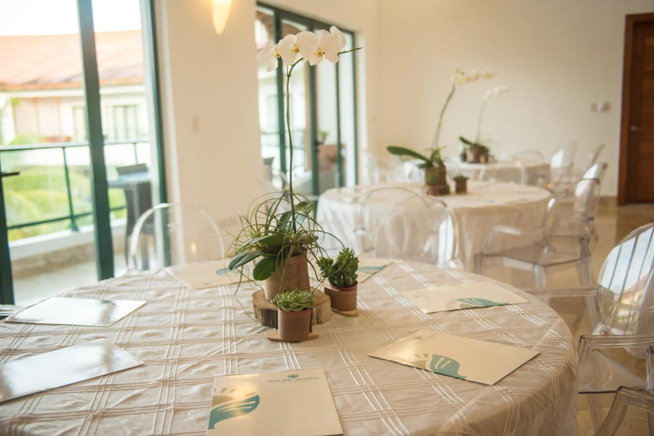 Wedding reception tables with white orchids and ghost chairs at Sublime Samaná, Samana