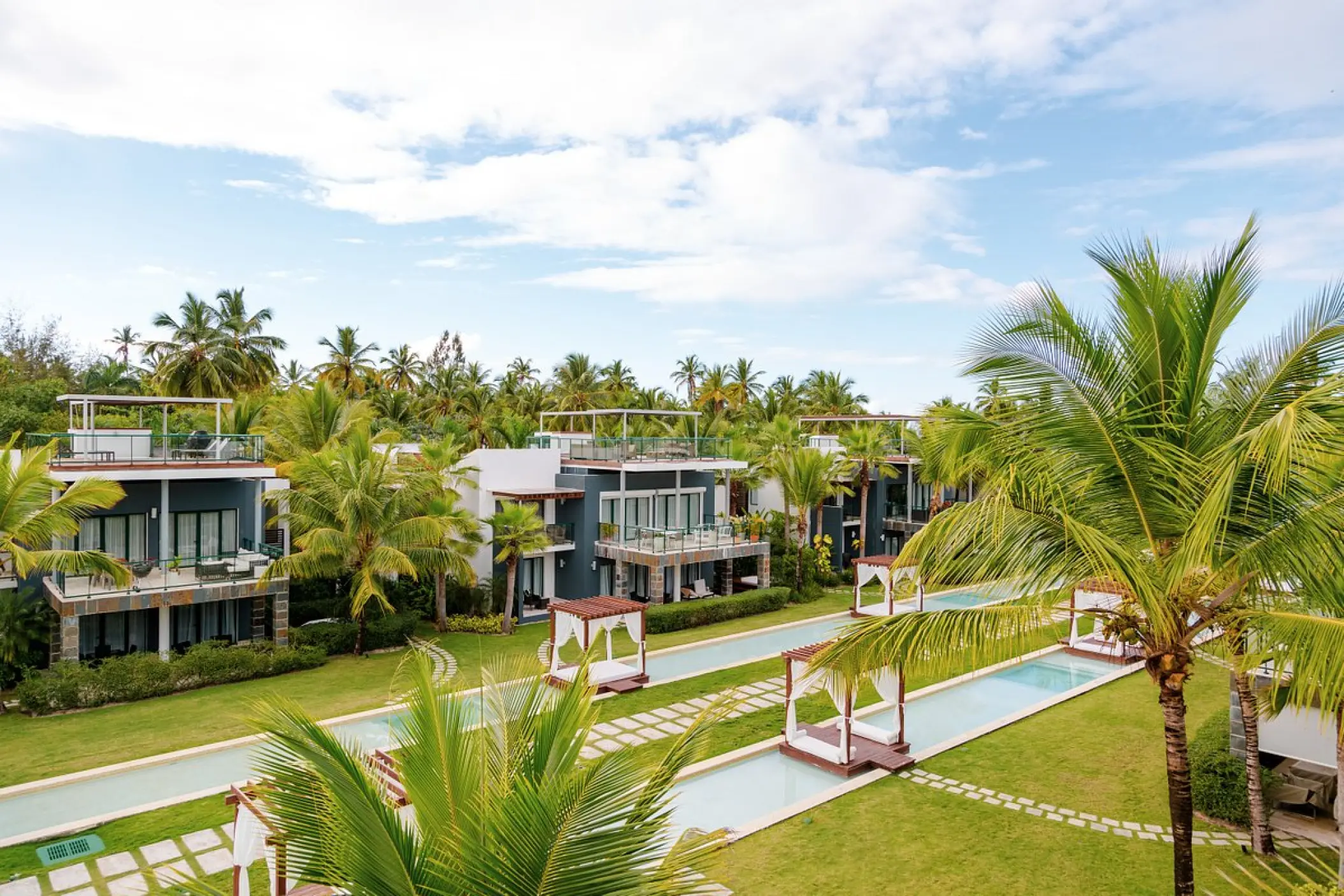 Resort suites and geometric swimming pools surrounded by palm trees at Sublime Samaná, Samana