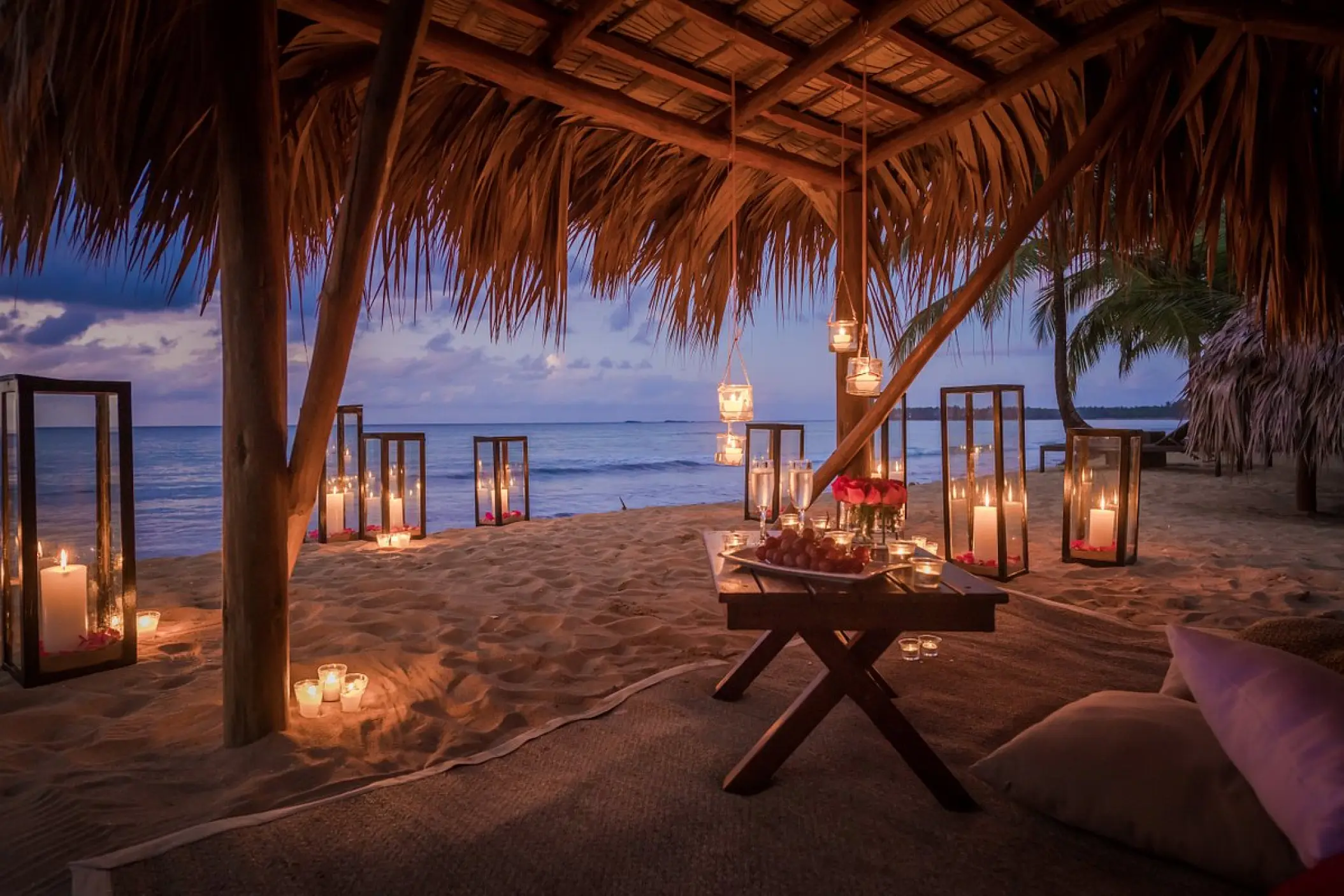Candlelit romantic dinner setup under a thatched palapa at Sublime Samana, Samana