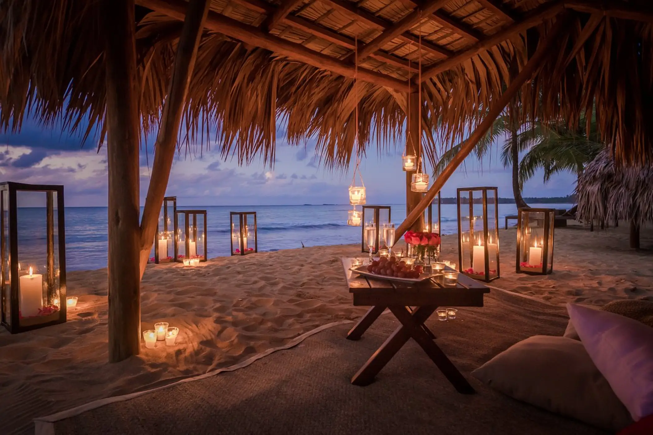 Candlelit romantic dinner setup under a thatched palapa at Sublime Samana, Samana