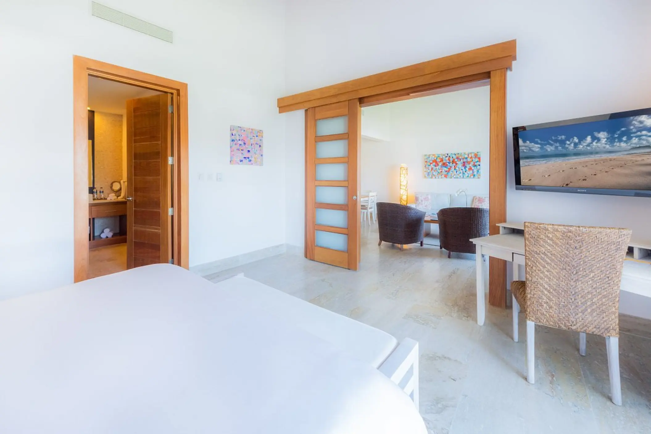 Modern suite with white bedding and wooden sliding doors at Sublime Samaná, Samana