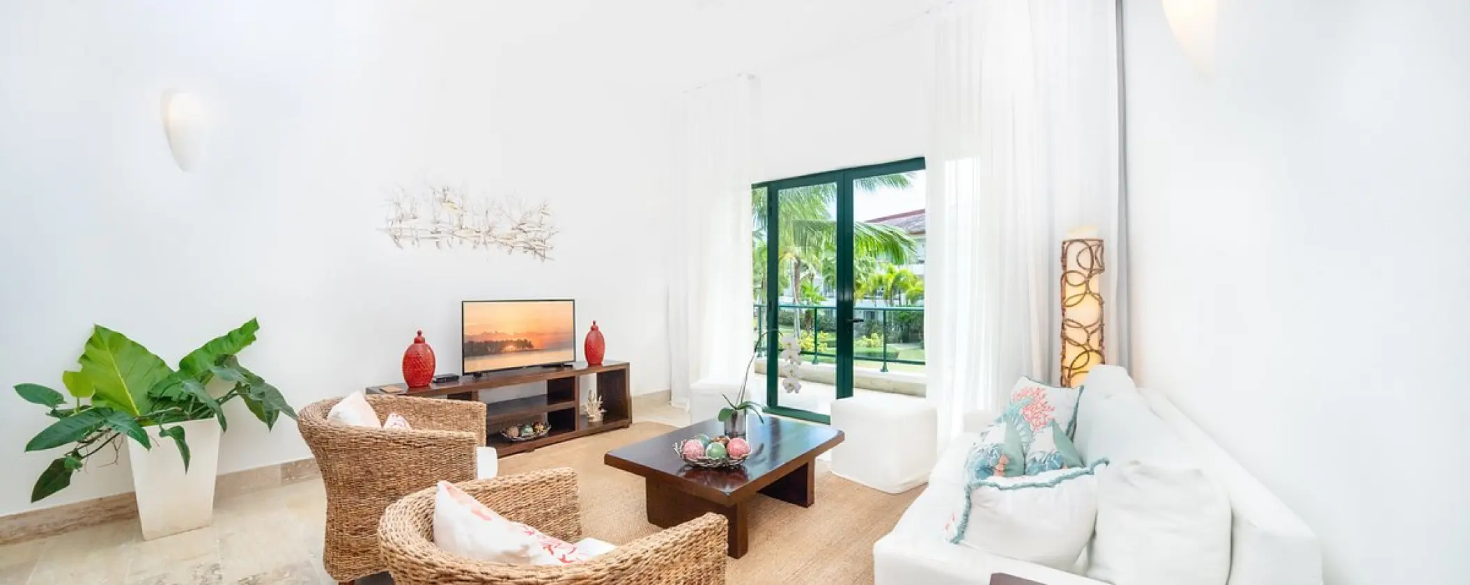 Two-bedroom suite living area with wicker chairs and terrace view at Sublime Samaná, Samana