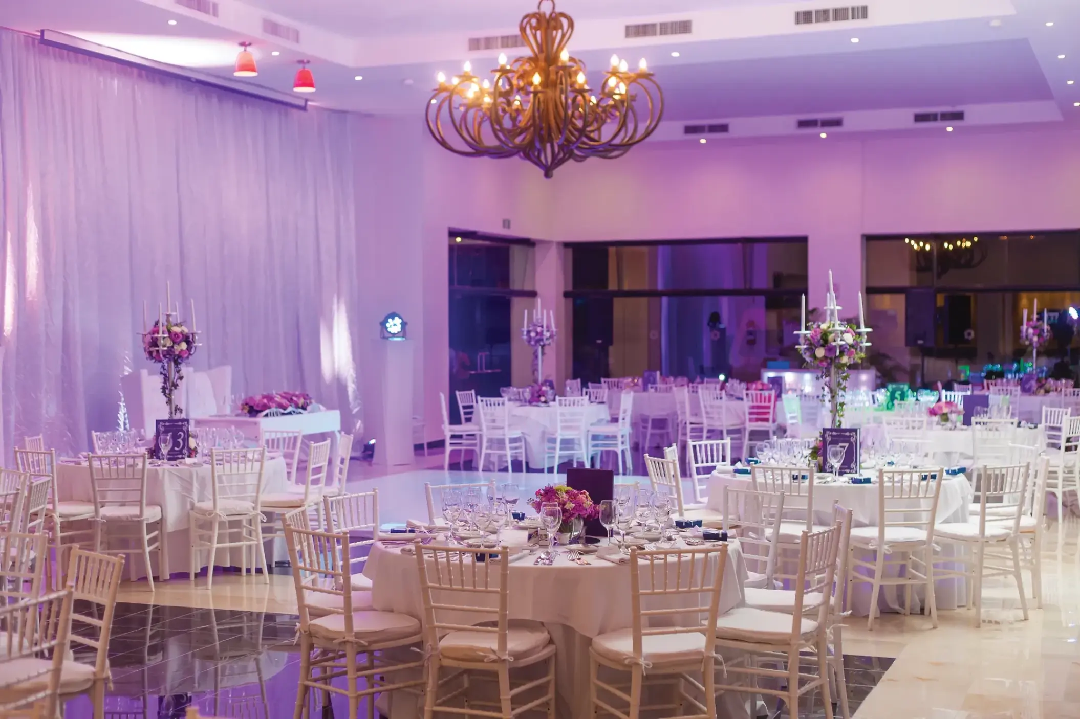Indoor wedding reception setup with purple lighting in the ballroom at Sunscape Akumal, Tulum
