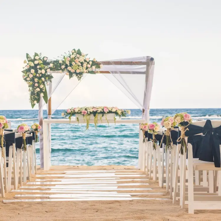 Beachfront wedding ceremony with a floral gazebo and white chairs at Sunscape Akumal, Tulum