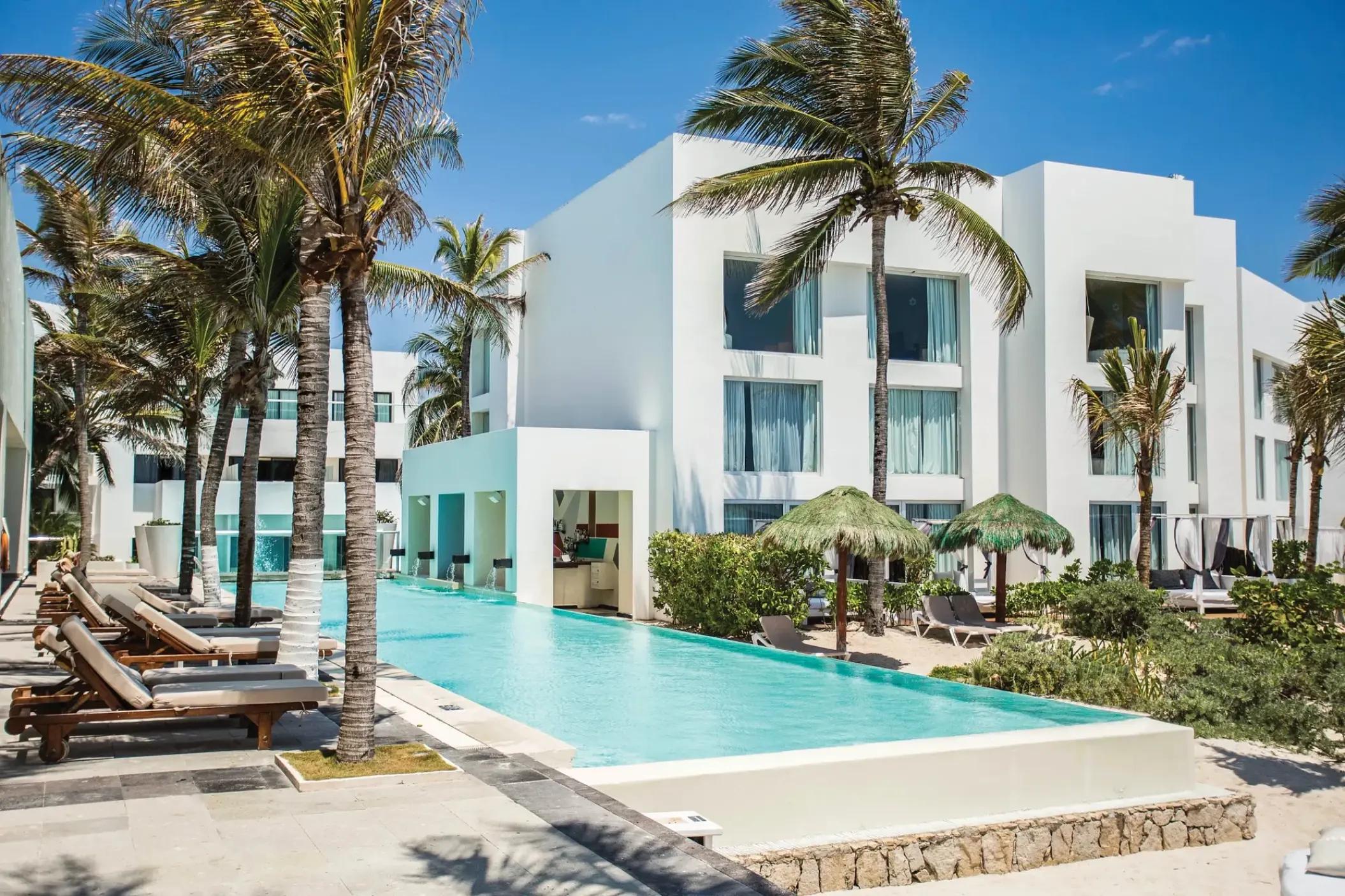 Sunscape Akumal Beach infinity pool and white buildings with palm trees, Tulum