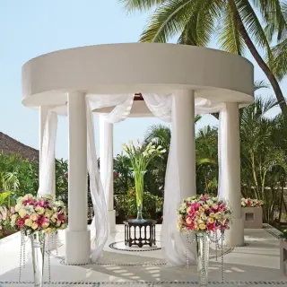 White wedding gazebo with floral arrangements and draped fabric at Sunscape Akumal Beach, Tulum