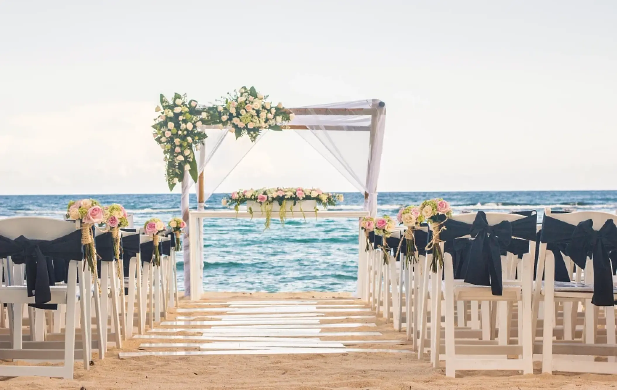 Beachfront wedding ceremony with a white gazebo and floral arrangements at Sunscape Akumal Beach, Tulum
