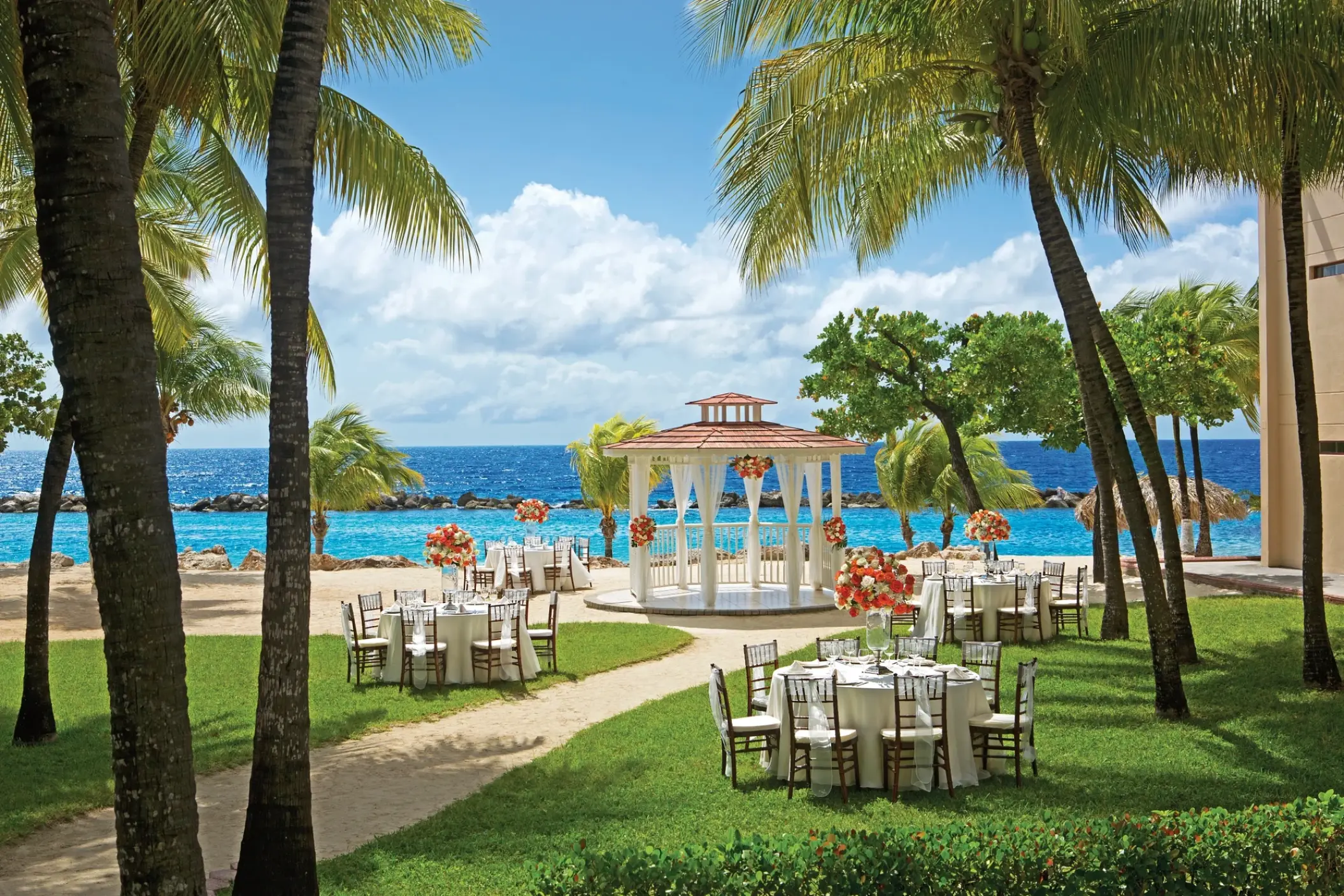 Beachfront wedding reception setup with white gazebo and garden tables at Sunscape Akumal Beach, Tulum