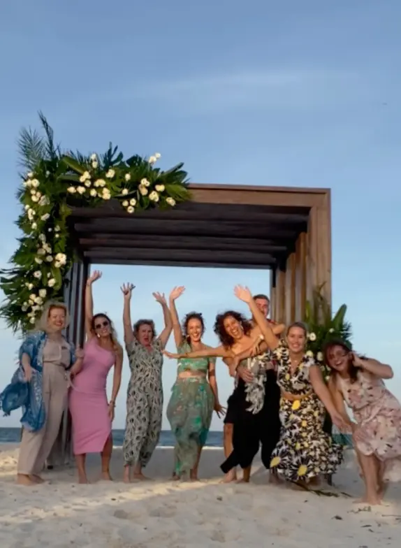 Paradise Weddings team members jumping and waving under a beach wedding gazebo