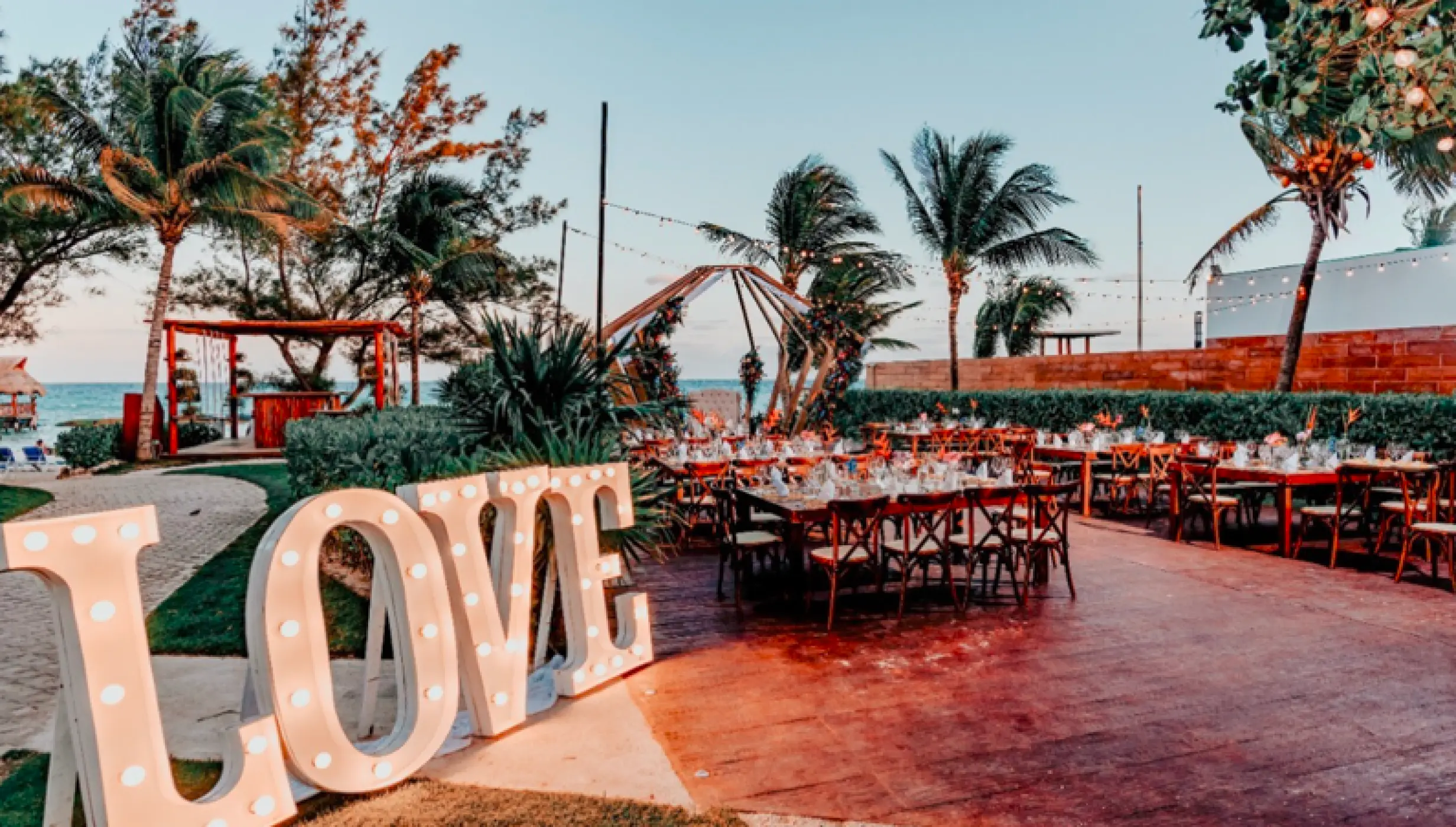 Outdoor wedding reception with marquee LOVE letters and wooden tables at The Fives Beach, Playa Del Carmen