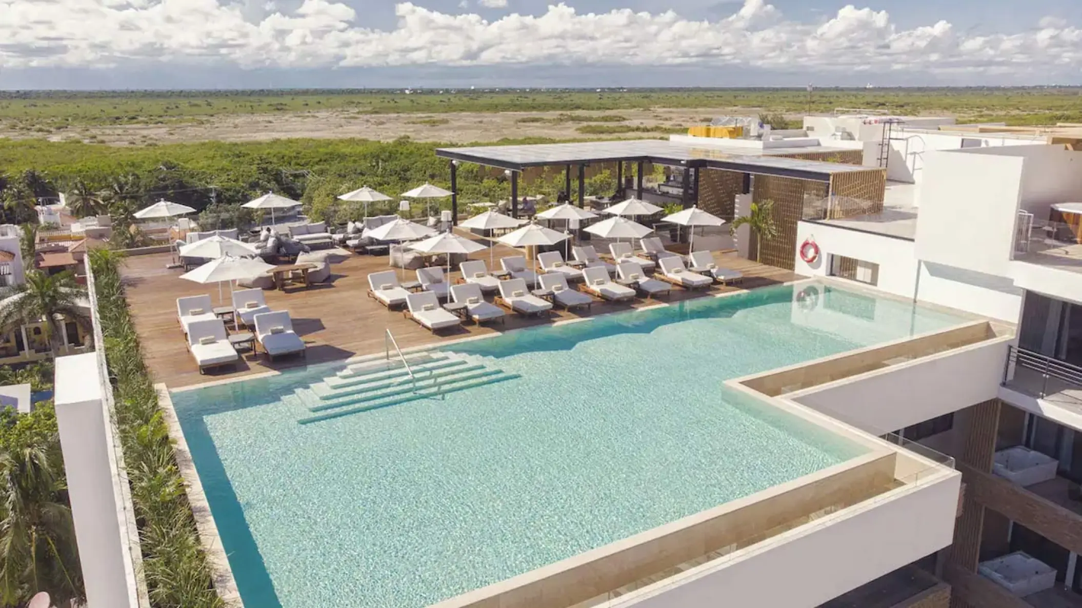 Rooftop infinity pool with white sun loungers and umbrellas at The Fives Oceanfront, Riviera Maya