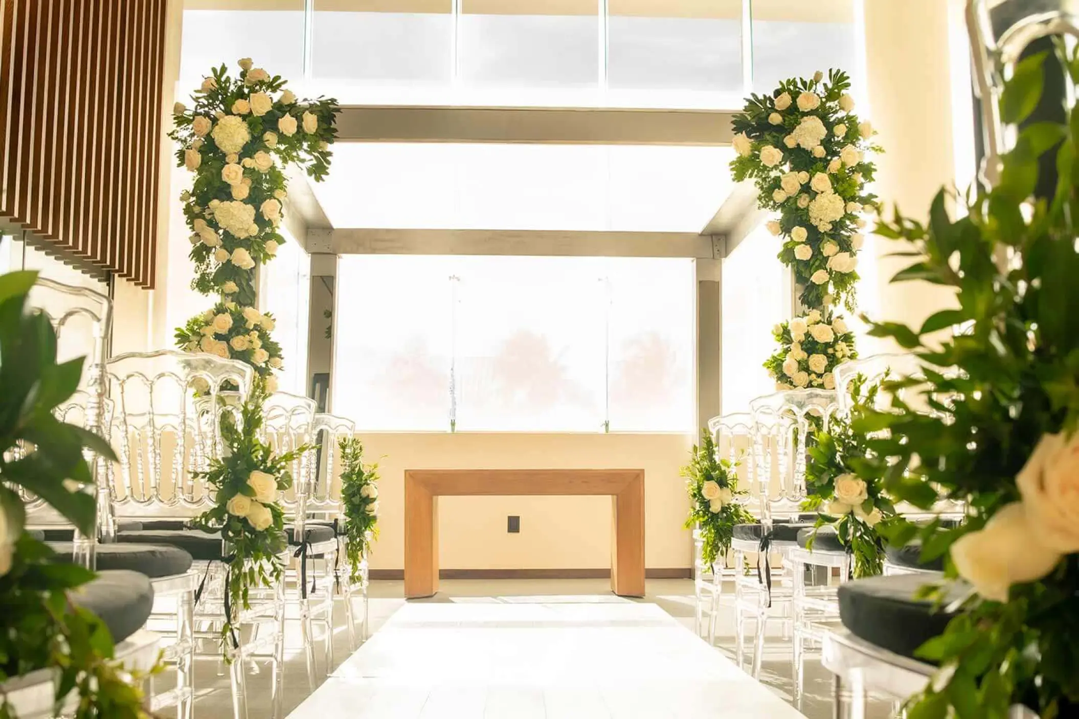 Indoor wedding ceremony with floral pillars and white aisle at The Fives Oceanfront, Riviera Maya