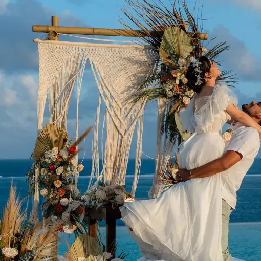 Groom lifting bride in front of a macrame arch at The Fives Oceanfront, Riviera Maya