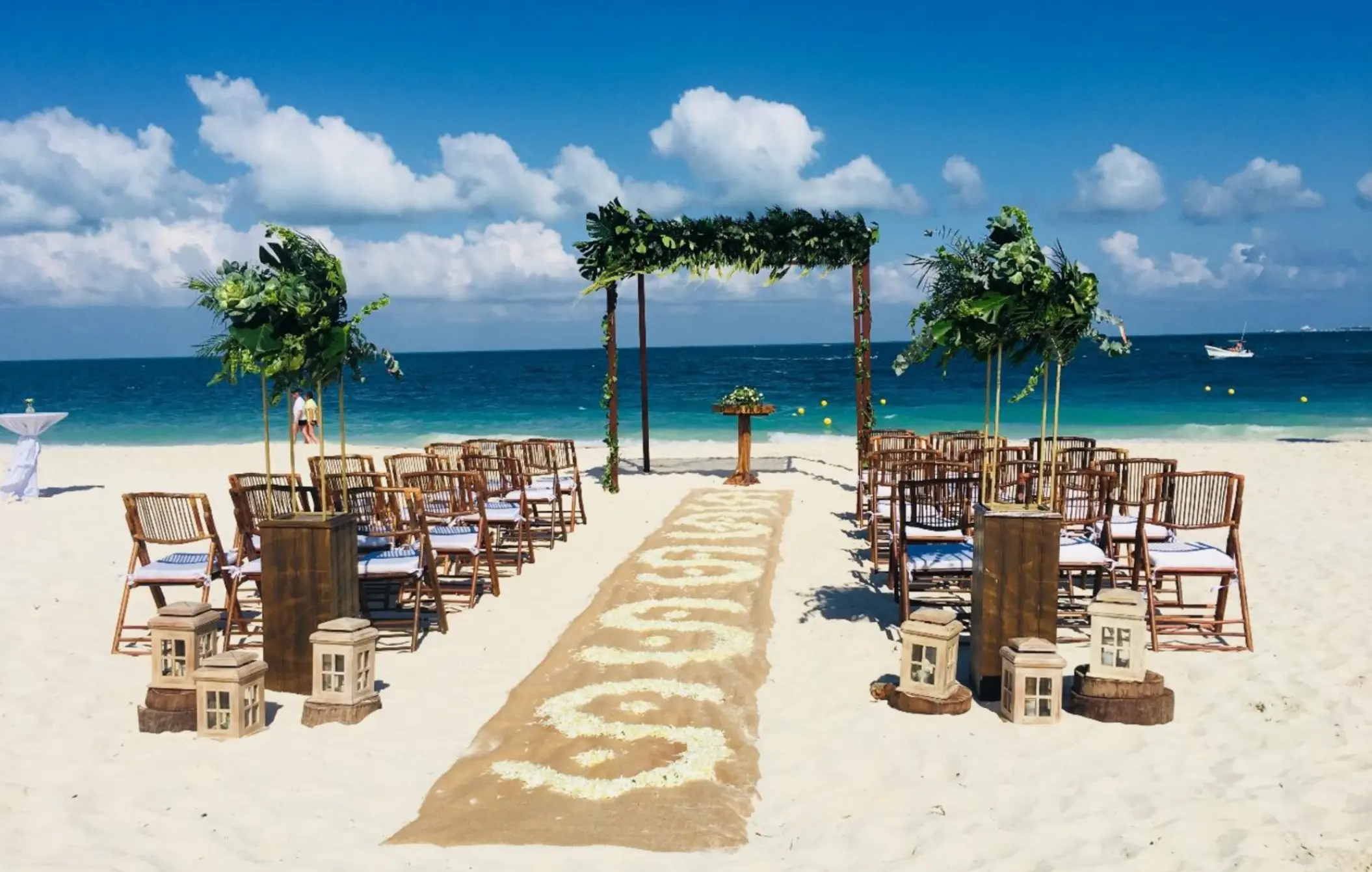 Beachfront wedding ceremony with wooden arch and aisle runner at TRS Coral Hotel, Cancun