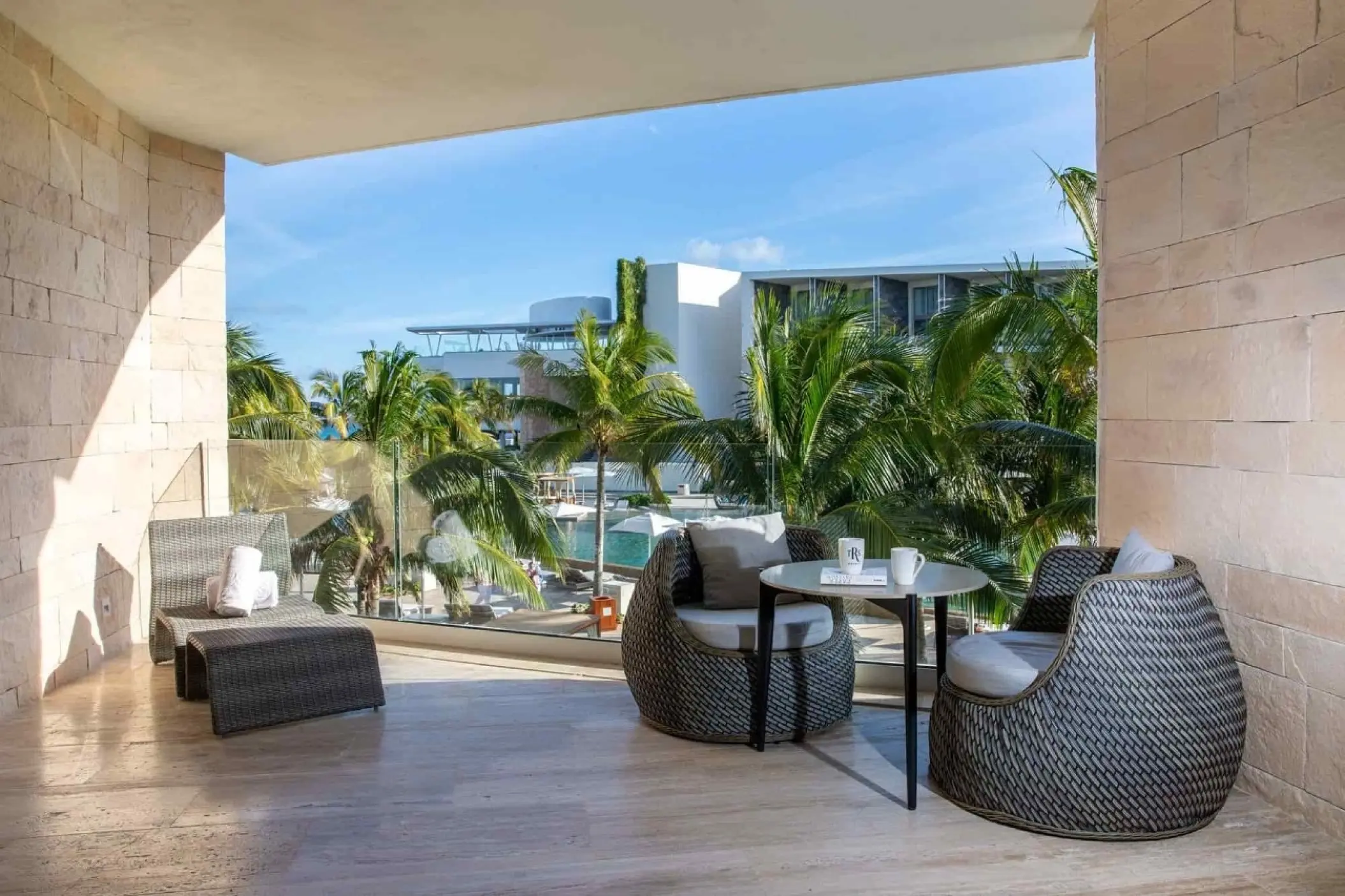 Junior suite terrace with wicker seating and garden views at TRS Coral Hotel, Cancun