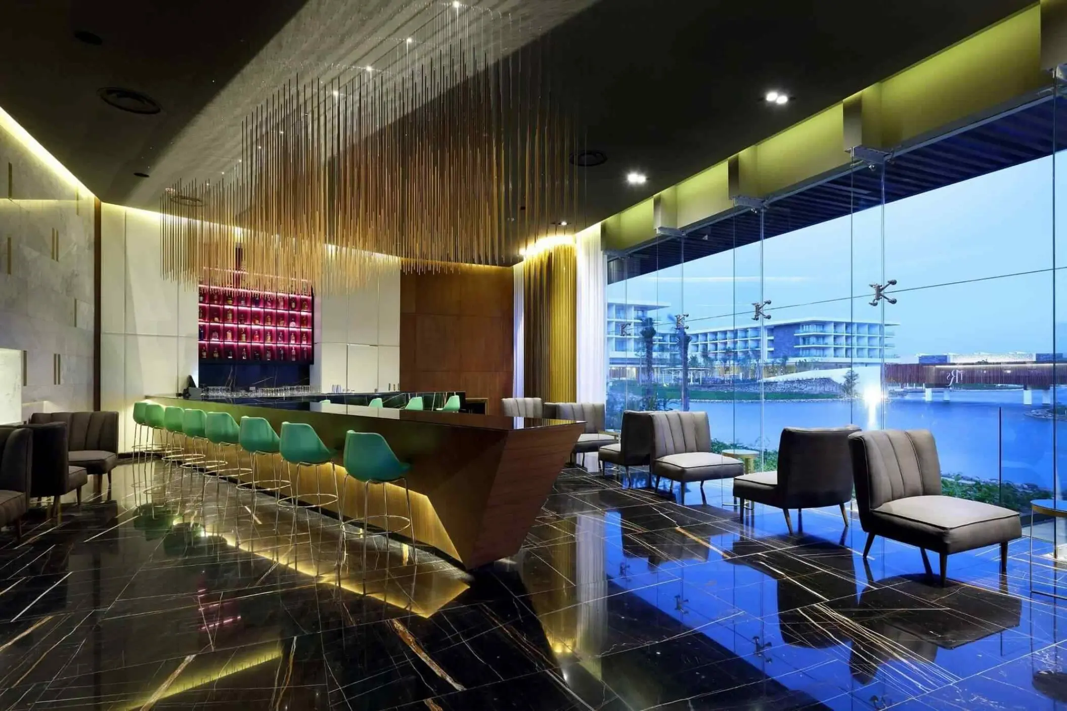 Modern lobby bar with teal stools and floor-to-ceiling windows at TRS Coral Hotel, Cancun