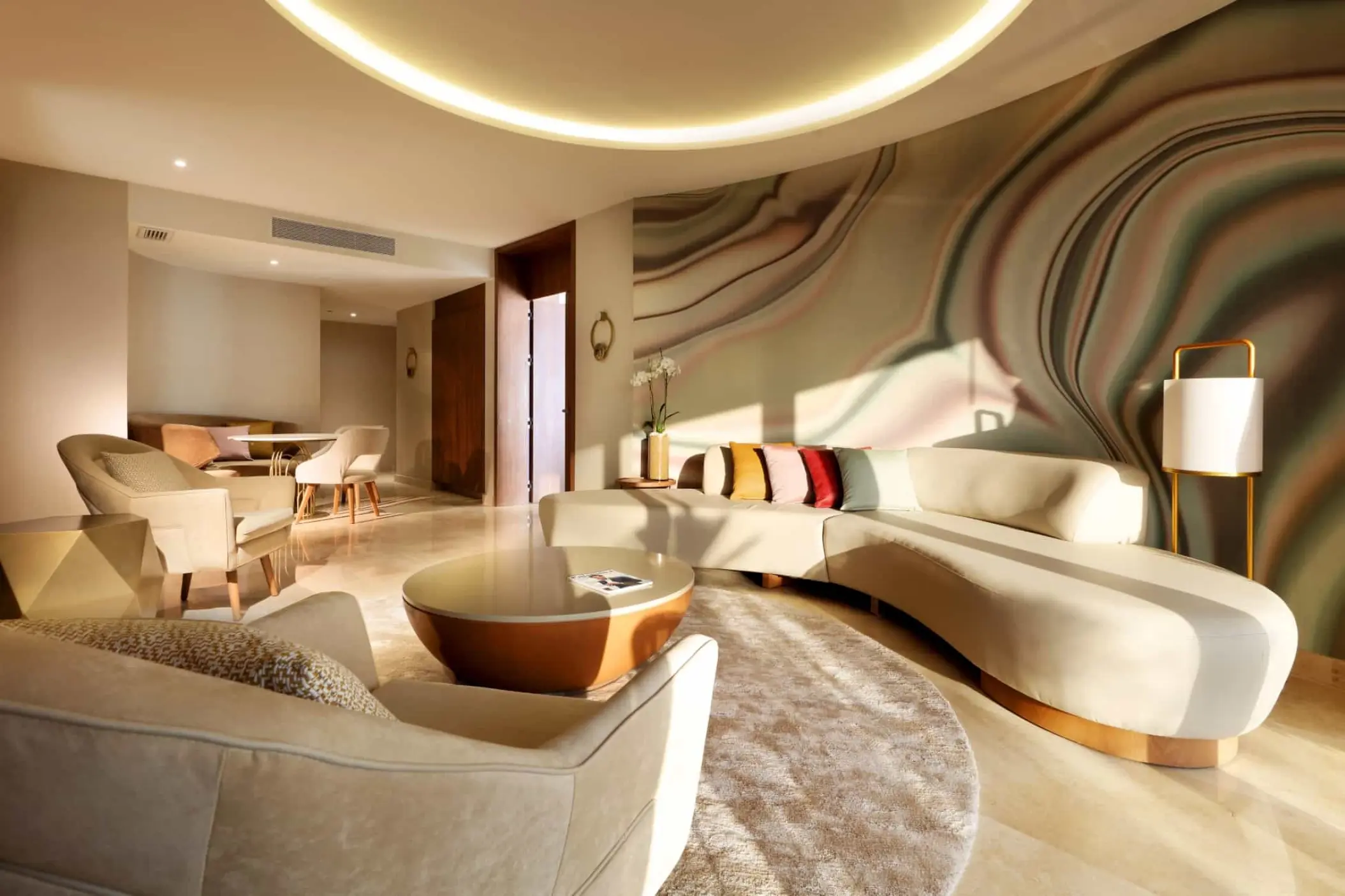 Signature Suite living area with curved sofa and abstract wall mural at TRS Coral Hotel, Cancun