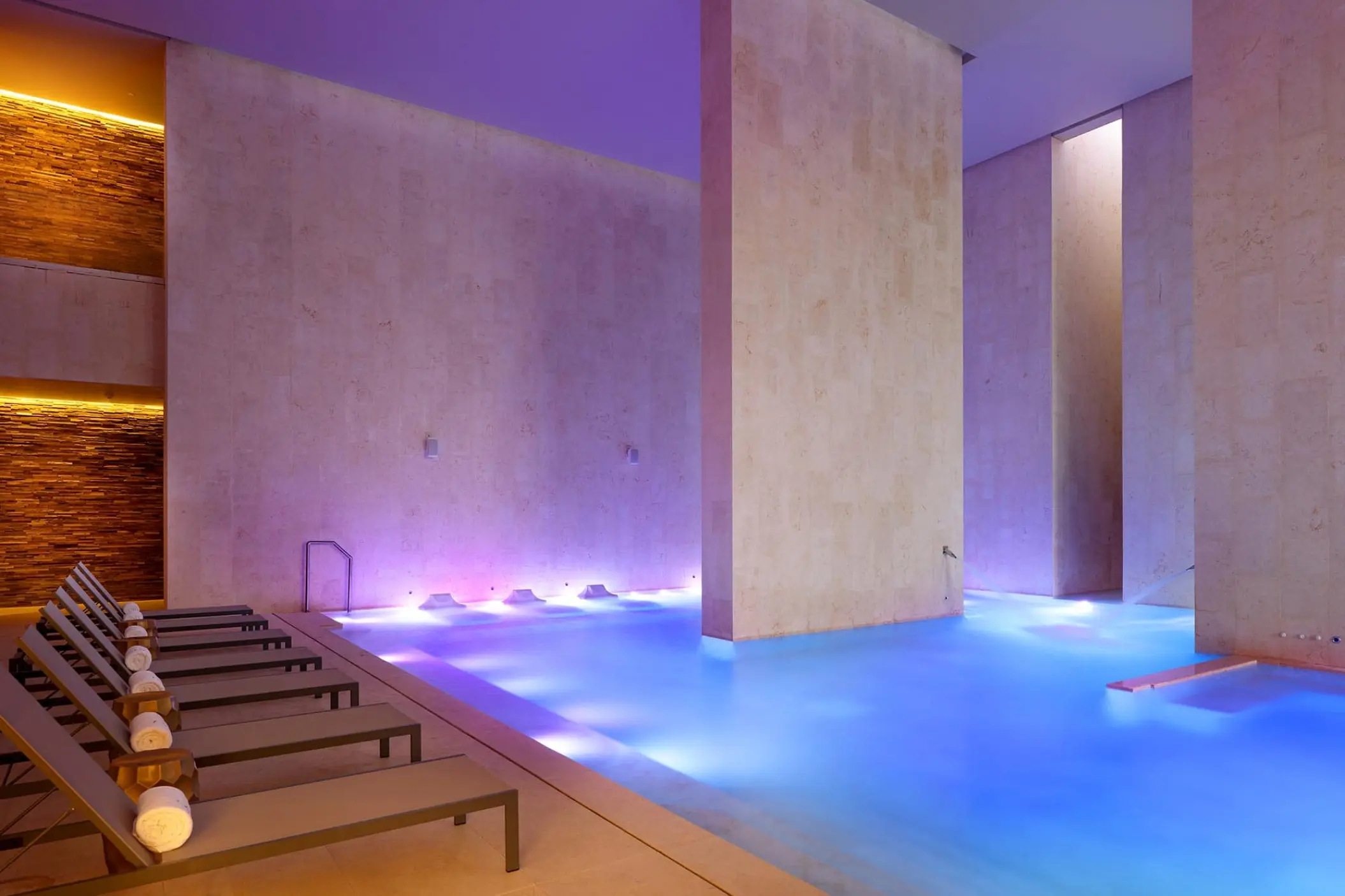Indoor spa pool with blue lighting and lounge chairs at TRS Coral Hotel, Cancun