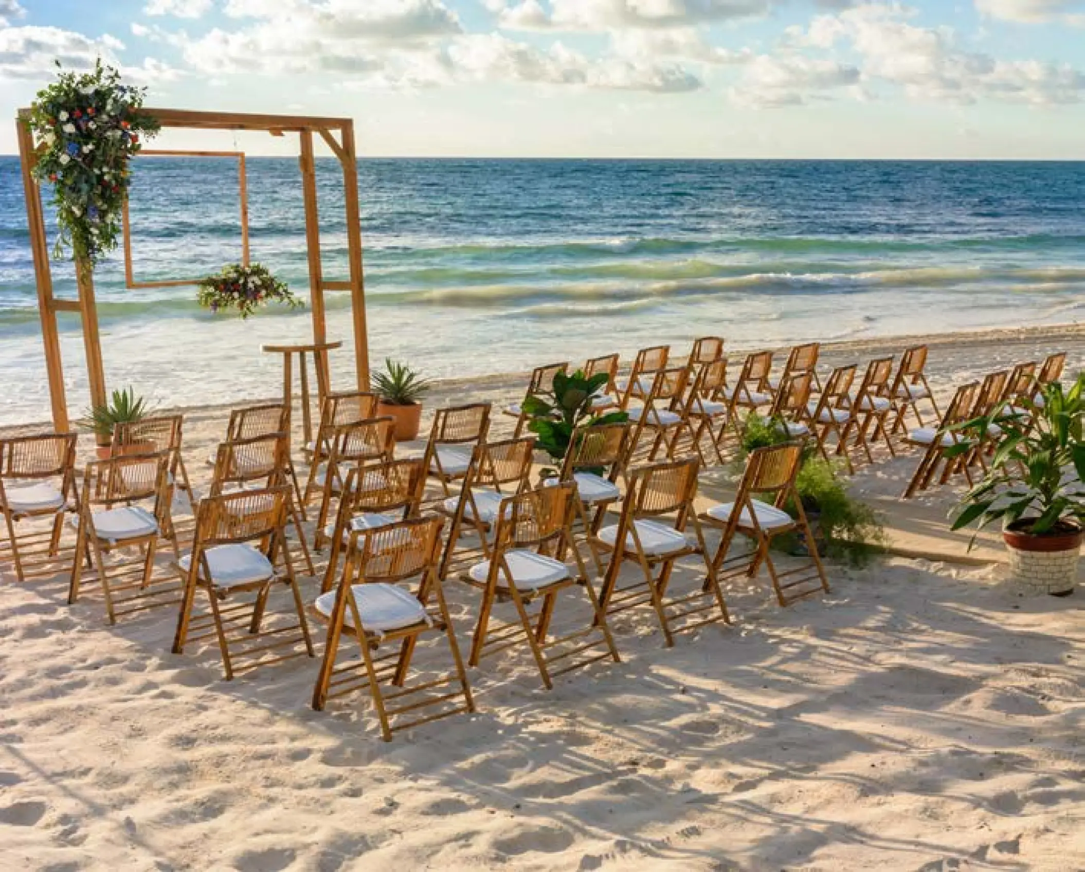 Beachfront wedding ceremony with wooden arch and chairs at UNICO 20°87°, Riviera Maya