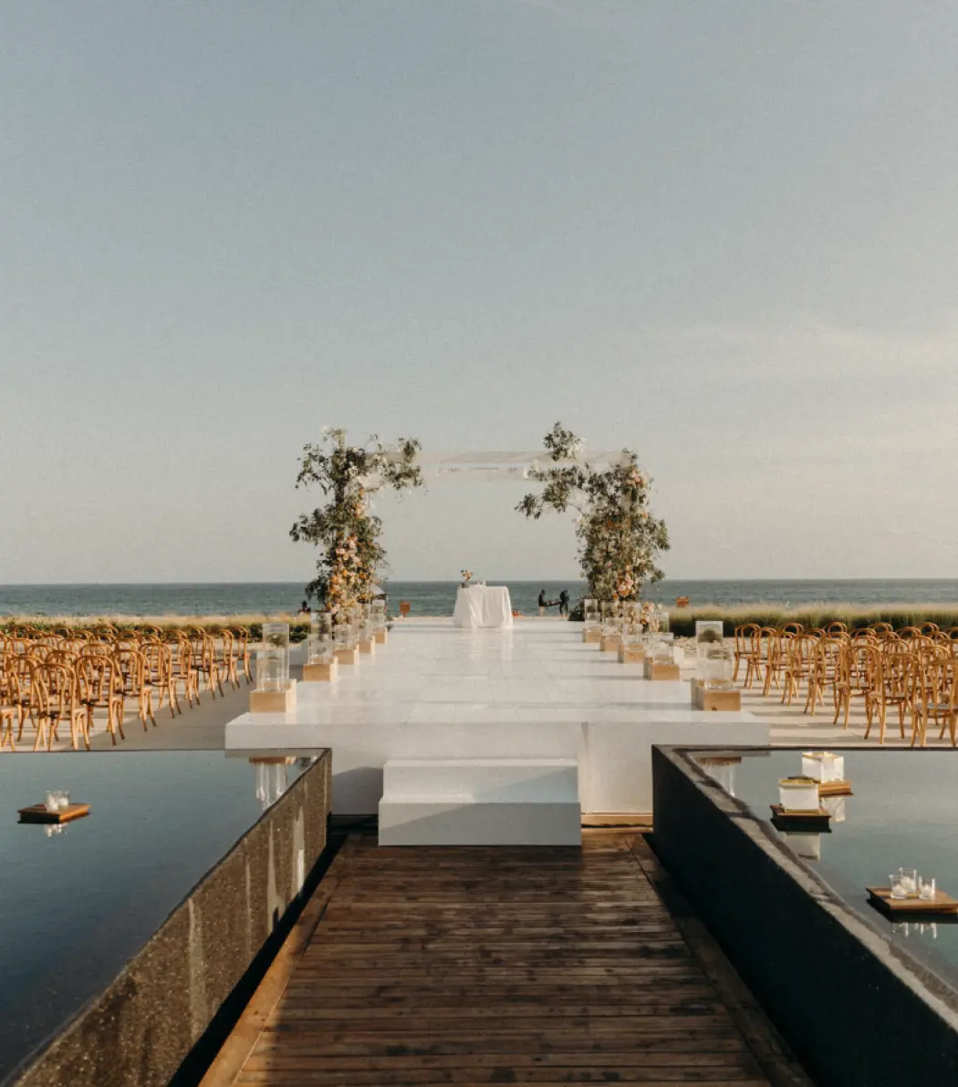 Beachfront wedding ceremony with a white aisle and floral arch at Viceroy Los Cabos, Cabo San Lucas