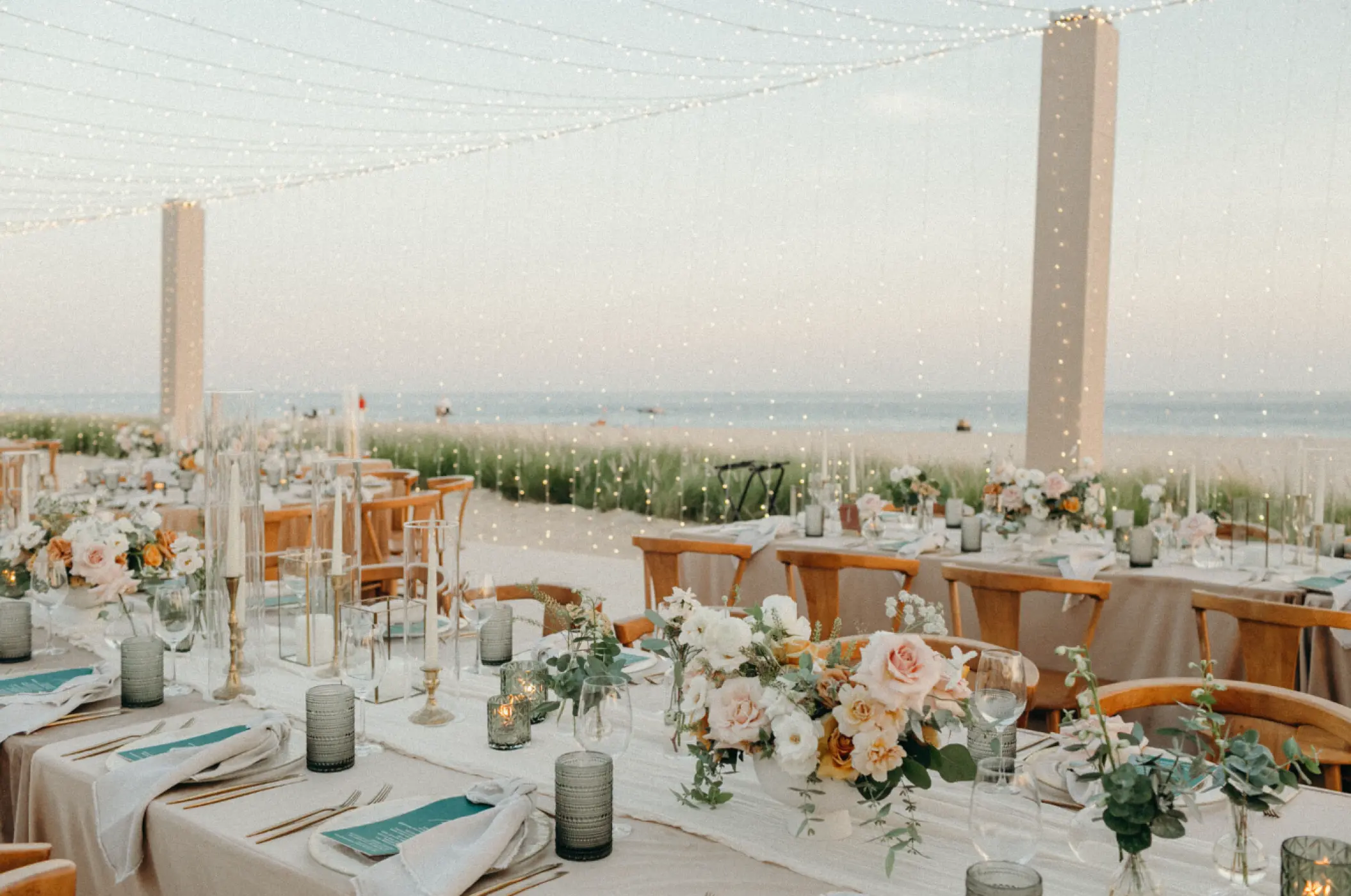Beachfront wedding reception setup with floral centerpieces and string lights at Viceroy Los Cabos, Cabo San Lucas