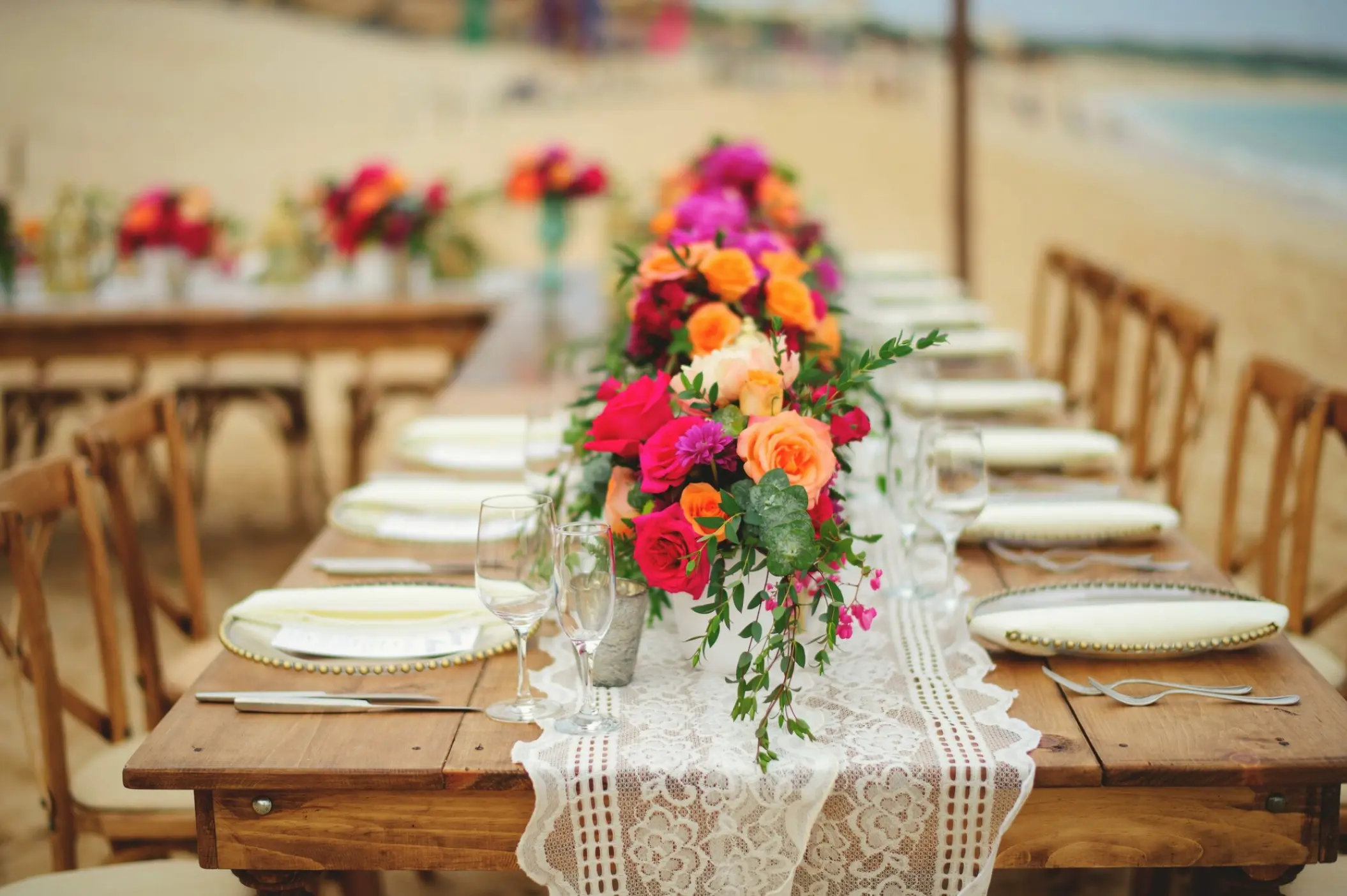 Long wooden table with lace runner and floral centerpiece for a beach reception at Villa La Estancia, Cabo San Lucas