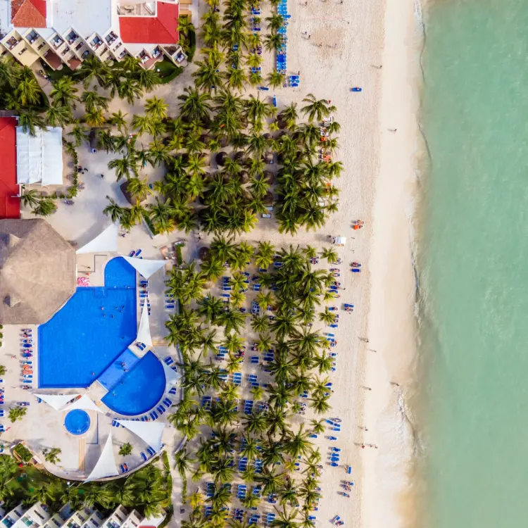 Aerial view of Viva Maya by Wyndham pools, palm trees, and white sand beach, Playa Del Carmen