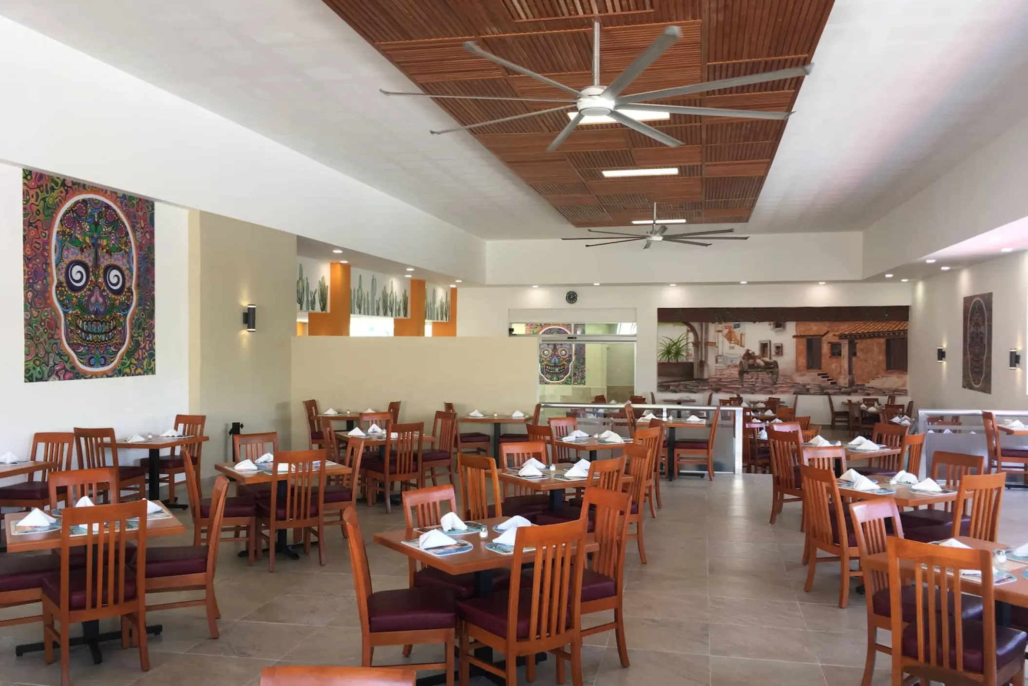 Indoor restaurant dining area with wooden tables and skull wall art at Viva Maya by Wyndham, Playa Del Carmen