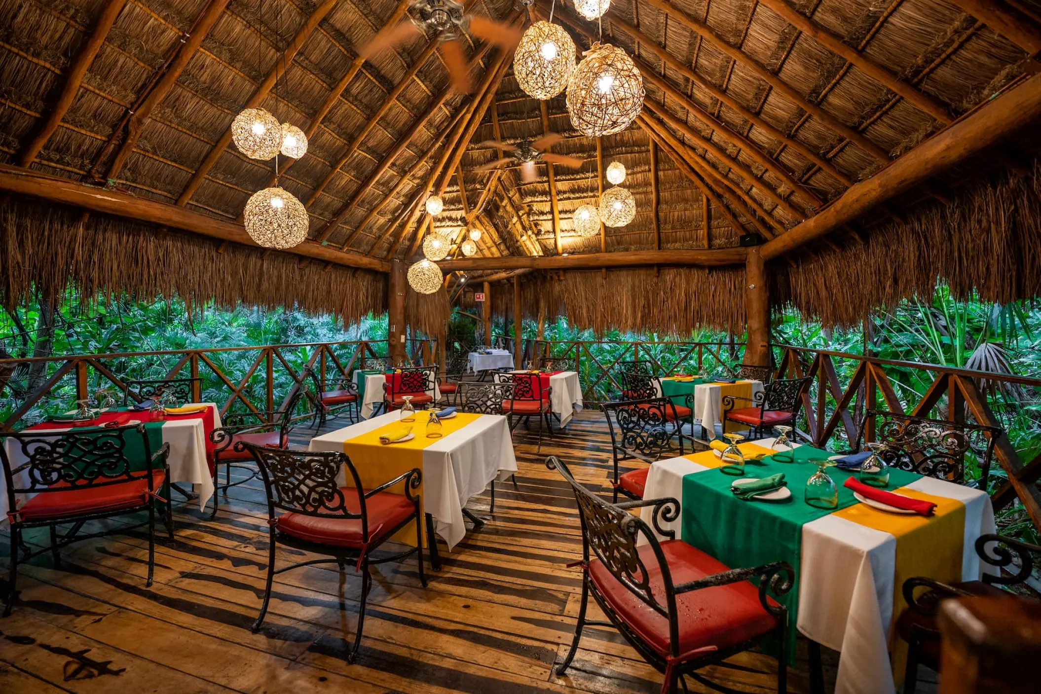 Palapa-roofed restaurant with hanging globe lights and colorful tables at Viva Maya by Wyndham, Playa Del Carmen