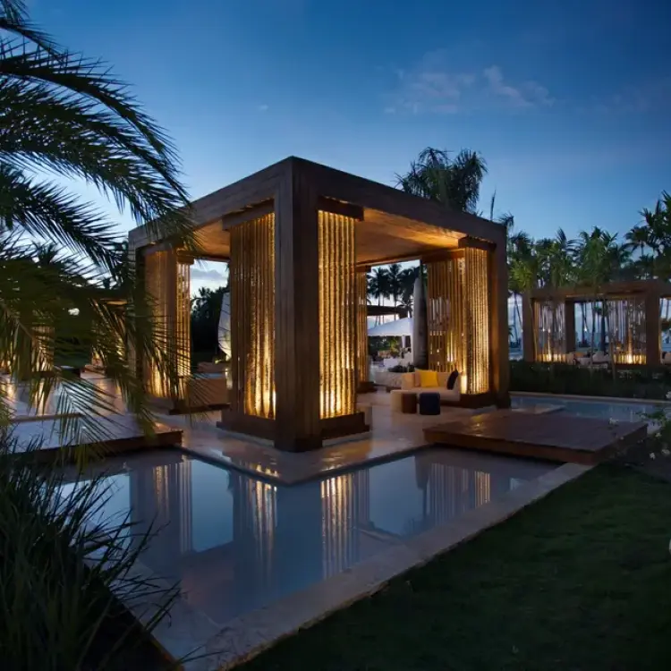 Lit wooden cabanas over water features at night at Viva V Samana, Samana