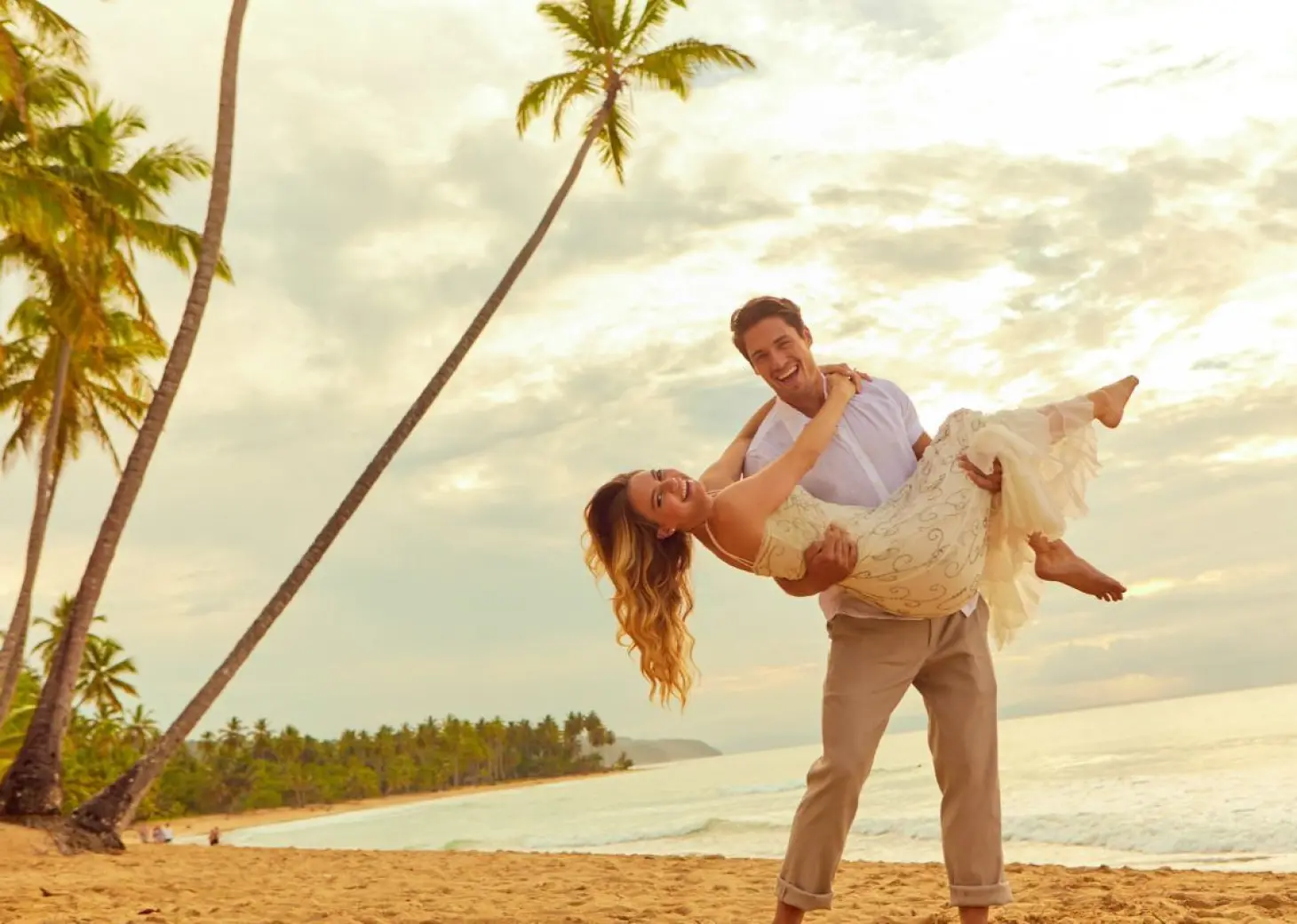 Groom carrying bride on a tropical beach at Viva V Samana, Samana