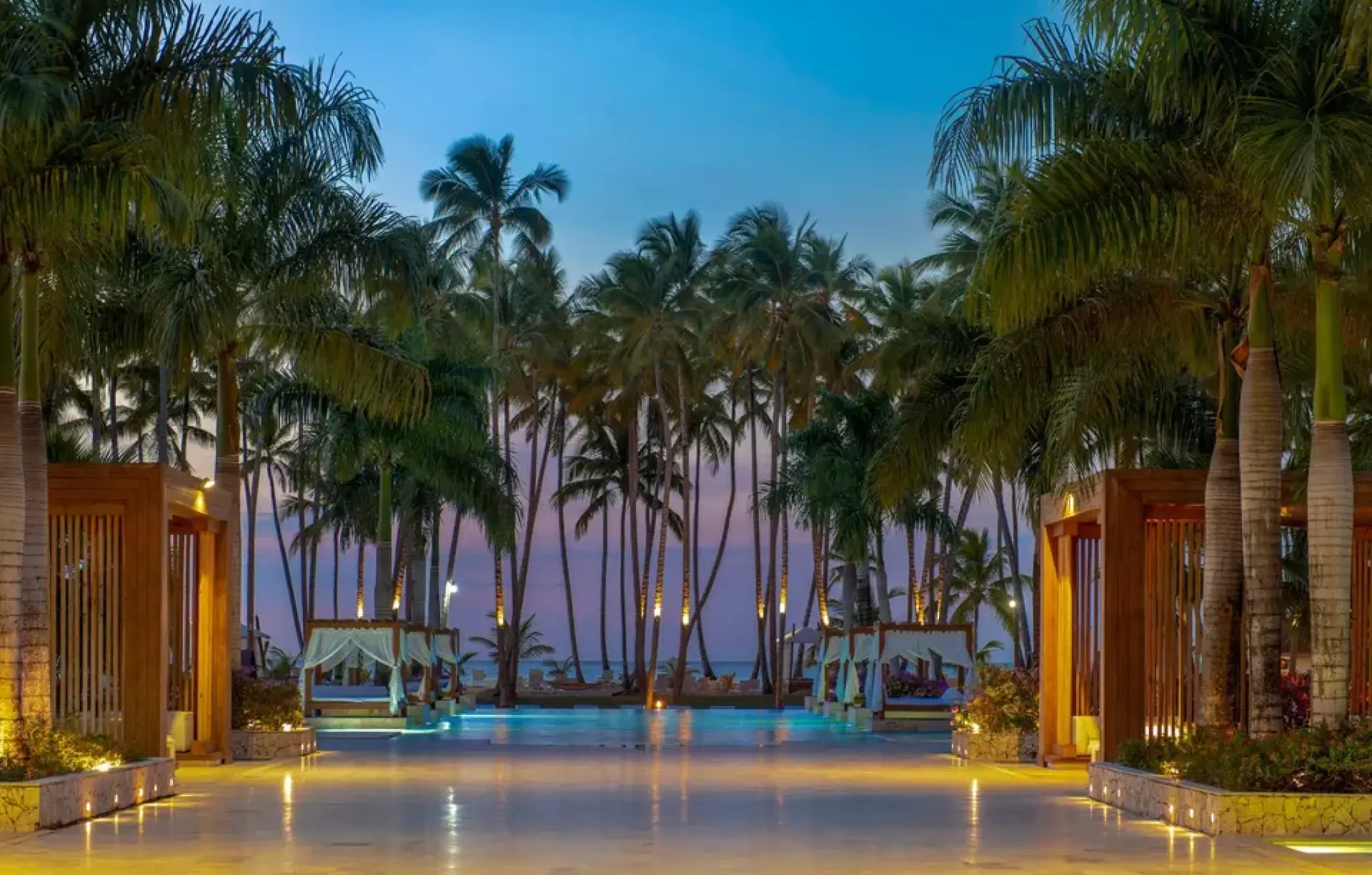 Illuminated main pool area at night with palm trees and cabanas at Viva V Samana, Samana