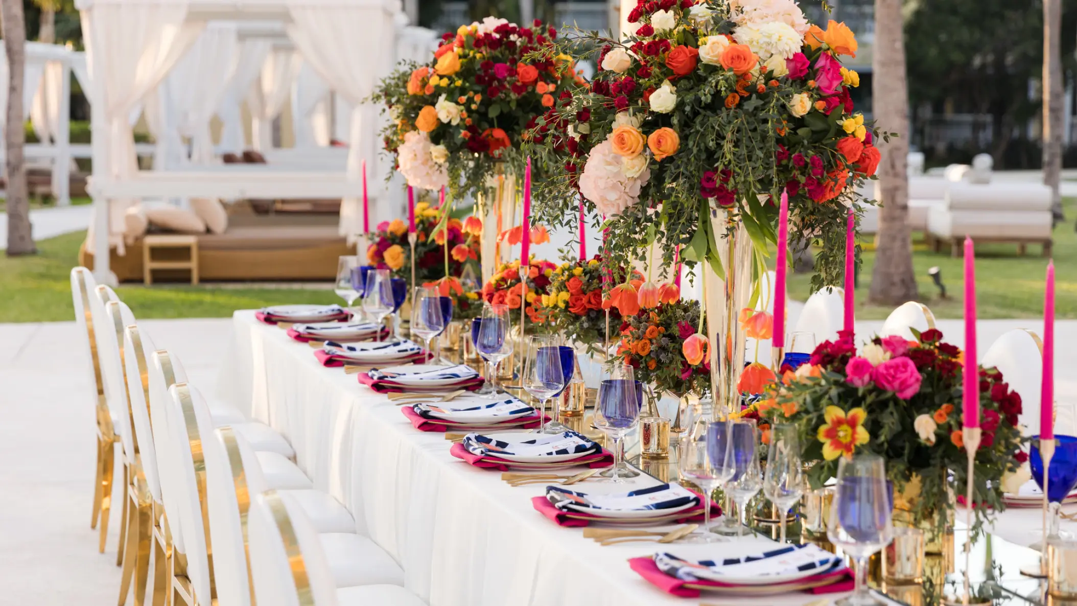 Long wedding reception table with colorful floral centerpieces and pink candles at Iberostar Selection Cancun