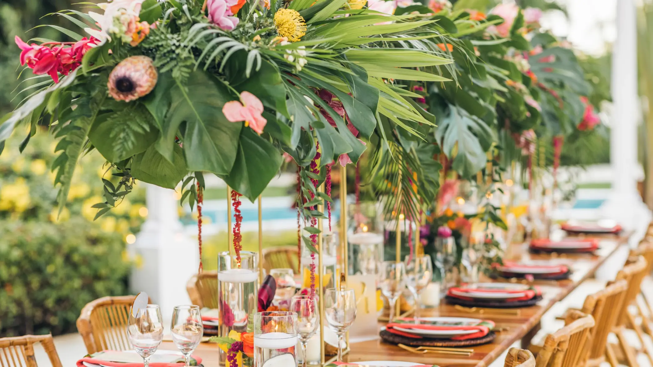 Tropical wedding reception table with floral centerpieces and monstera leaves at JOIA Paraiso, Riviera Maya