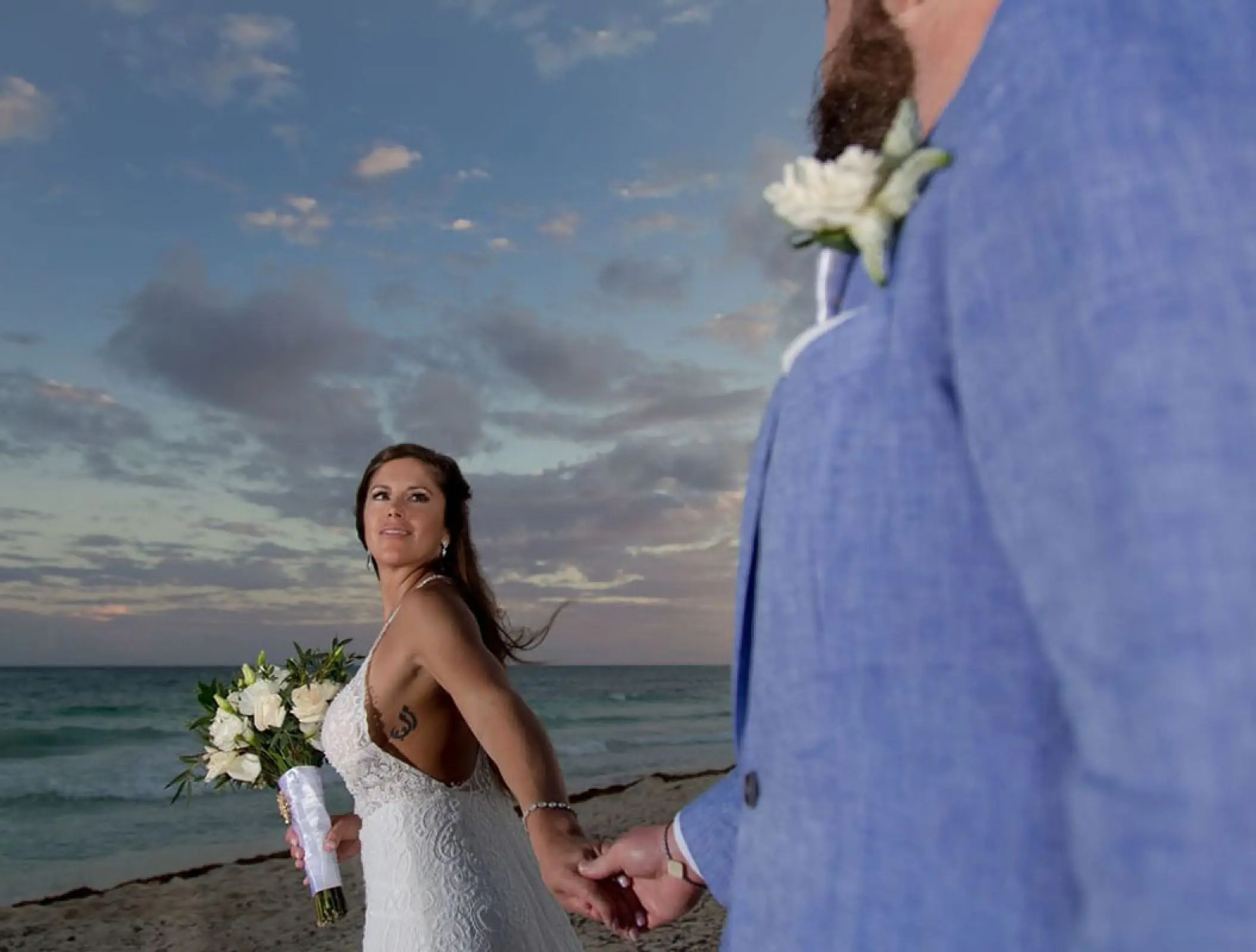 Bride holding hands with groom during a sunset beach vow renewal at Haven Riviera Cancun, Riviera Maya