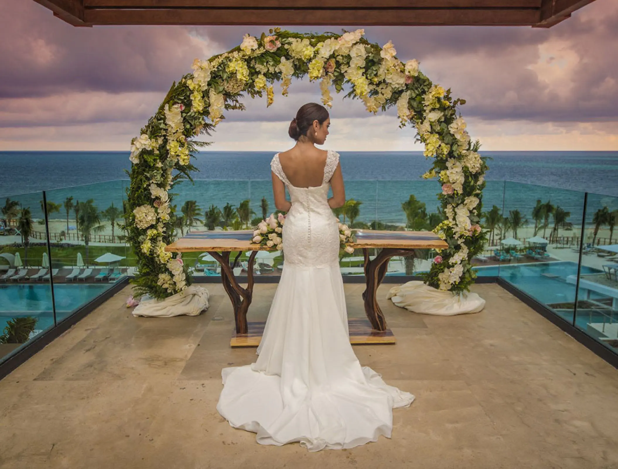 Bride under a floral wedding arch on a terrace at Haven Riviera Cancun, Riviera Maya