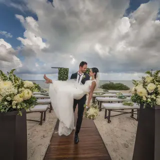 Groom carrying his bride at a beach ceremony at Haven Riviera Cancun, Riviera Maya