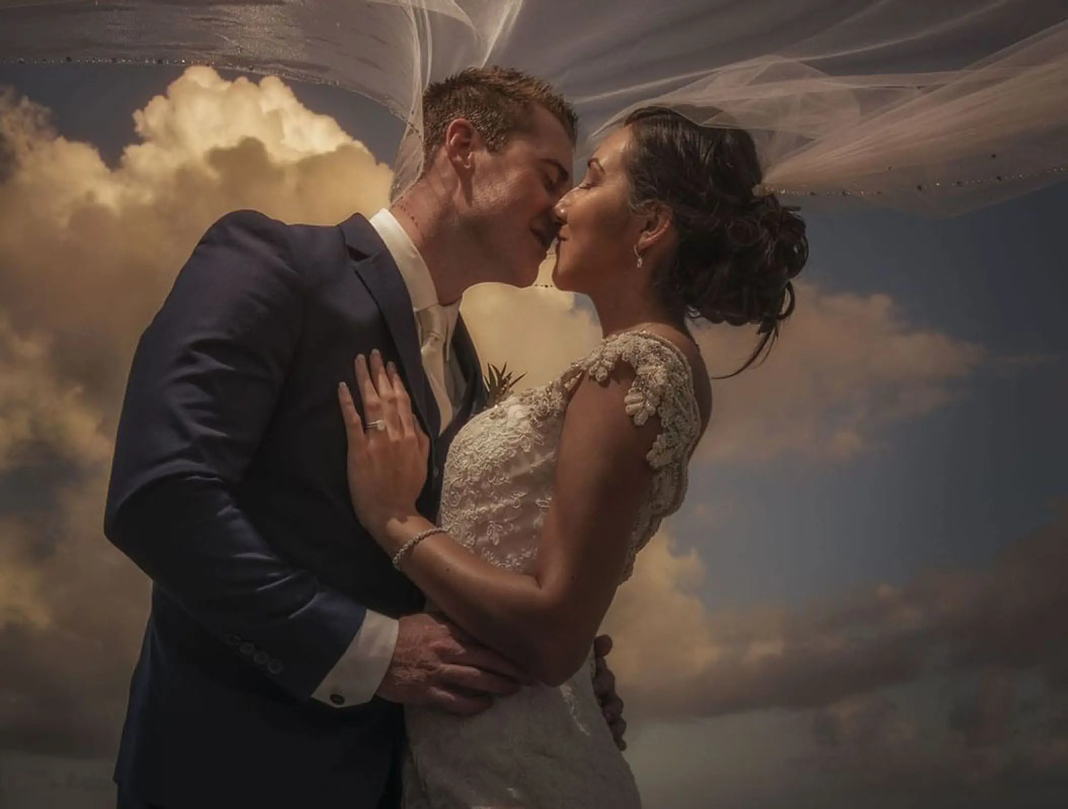 Bride and groom kissing under a blowing veil at Haven Riviera Cancun, Riviera Maya